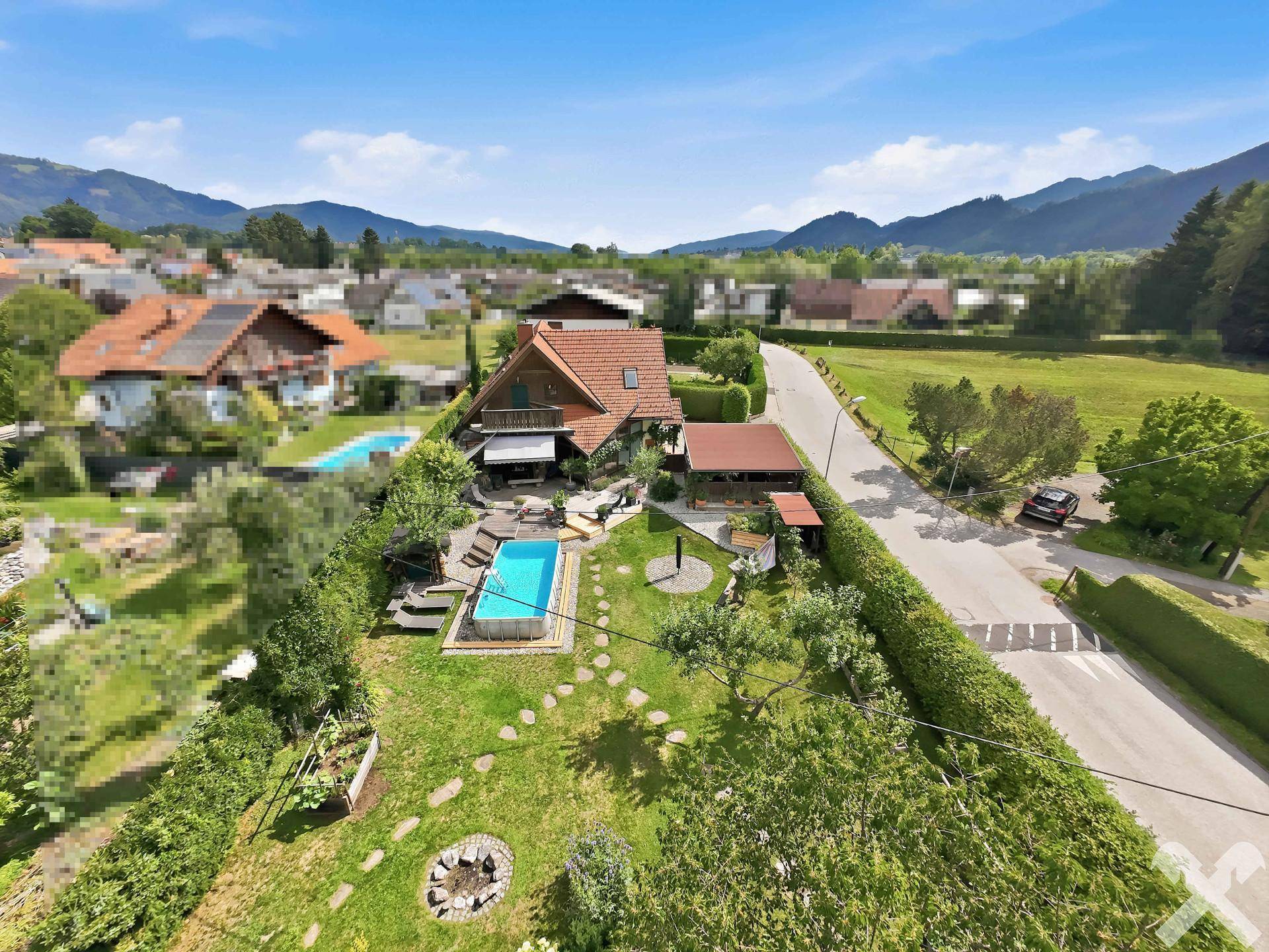Luftaufnahme des Hauses mit weitläufigem Grundstück, Poolbereich und Blick auf die umliegenden Berge.