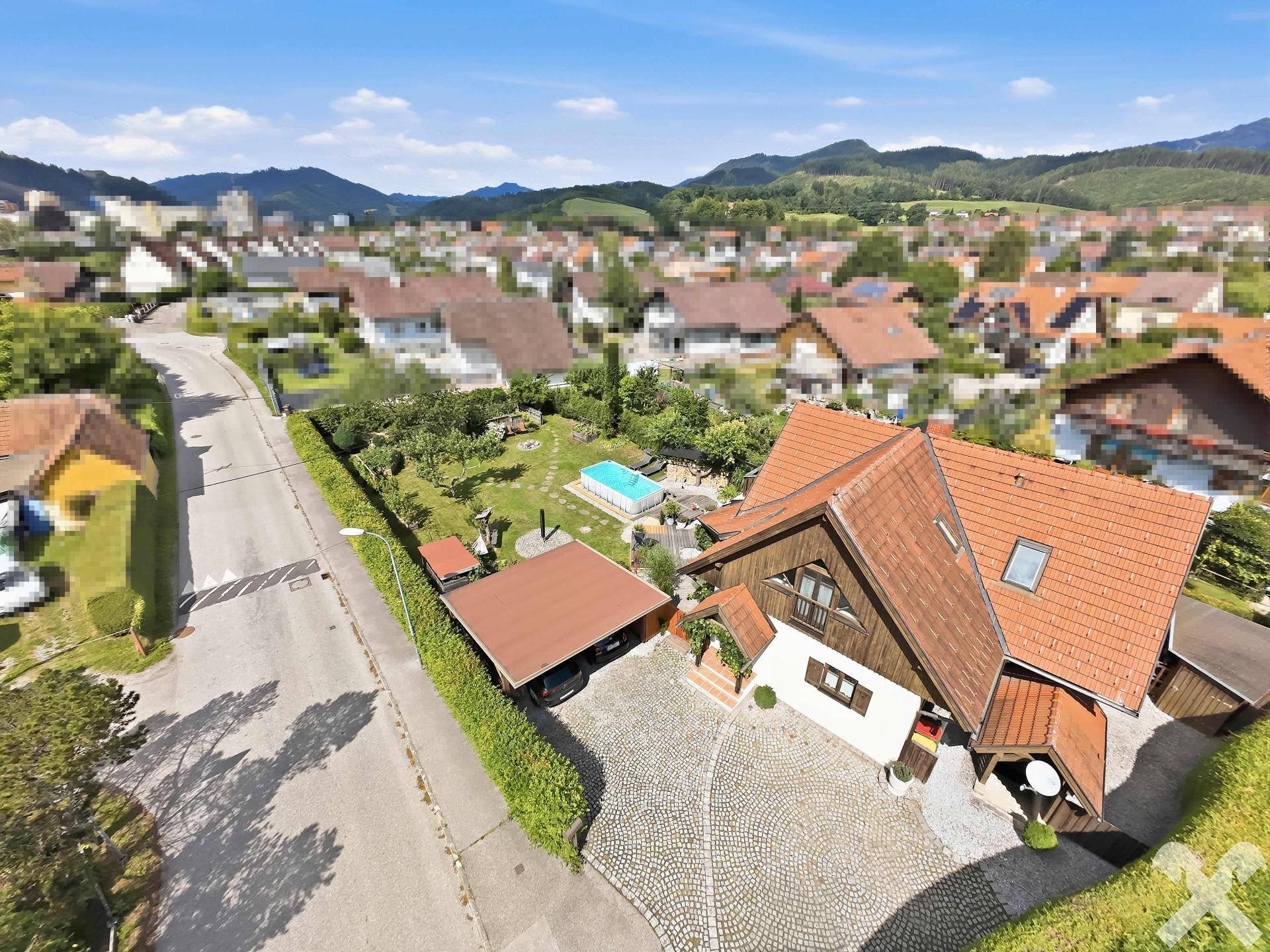 Luftaufnahme des Anwesens mit gepflasterter Auffahrt, Carport und dem Haus in ländlicher Umgebung.