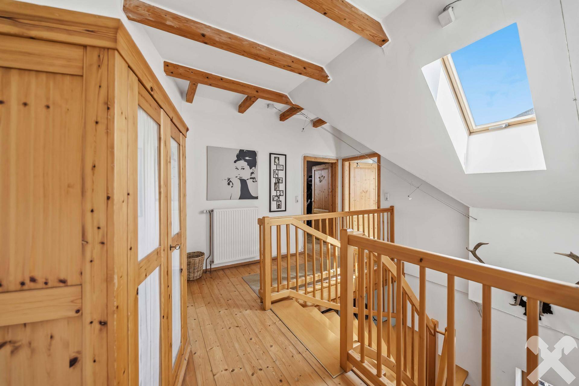 Heller Flur im Obergeschoss mit Holzboden, Dachfenster und Zugang zu weiteren Räumen.