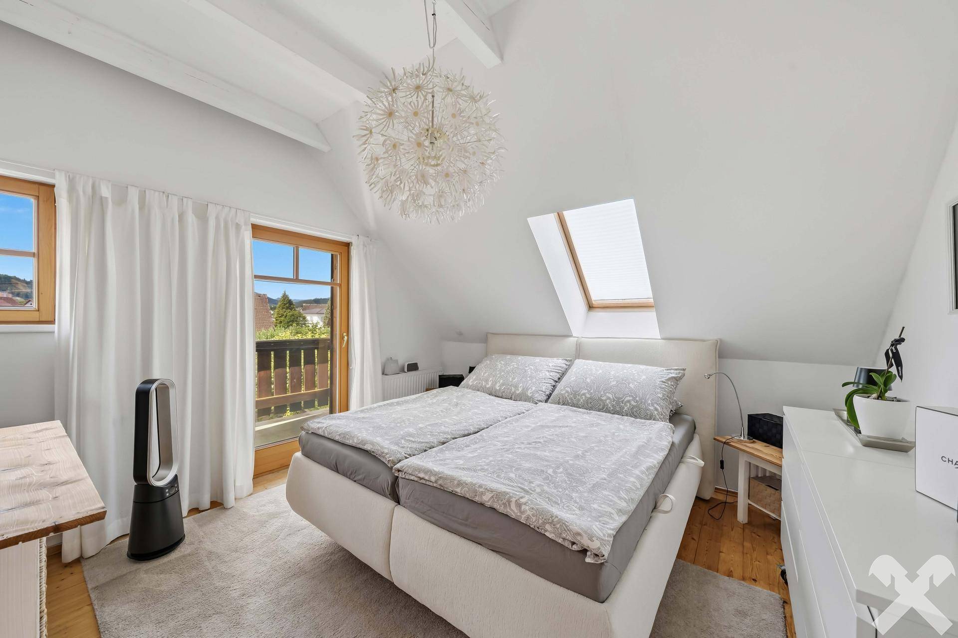 Gemütliches Schlafzimmer im Dachgeschoss mit Doppelbett, Dachfenster und Balkonzugang.