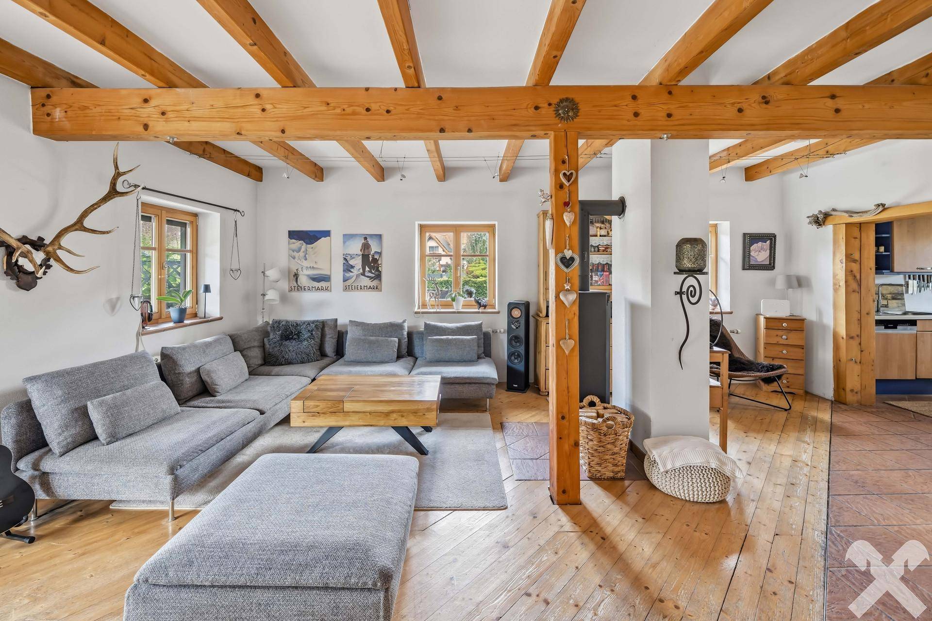 Geräumiges Wohnzimmer mit Holzbalkendecke, großem Sofa und rustikalen Dekorationselementen.