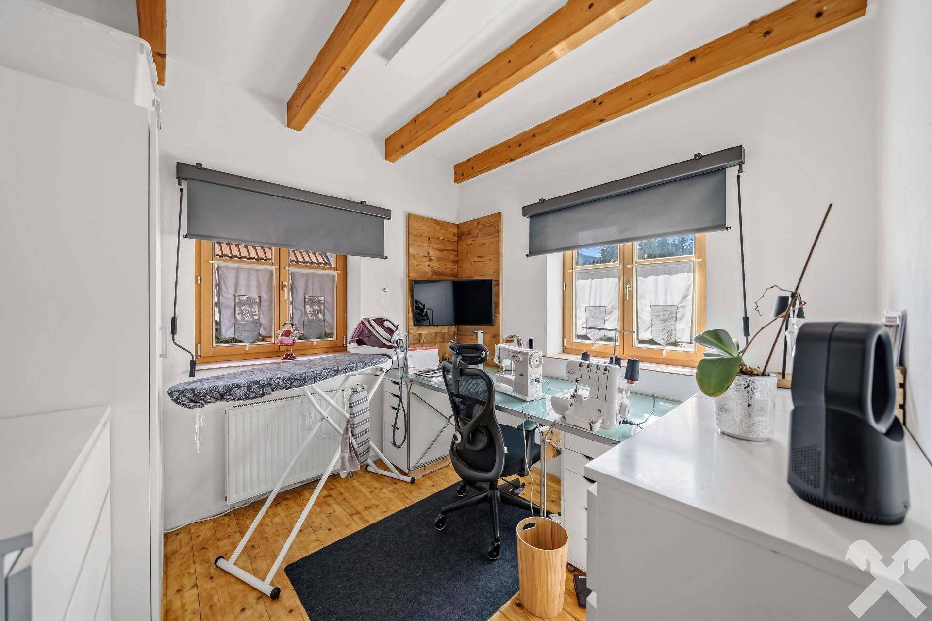 Helles Arbeitszimmer mit Holzbalken, zwei Fenstern und Nähmaschinen für Hobbys.