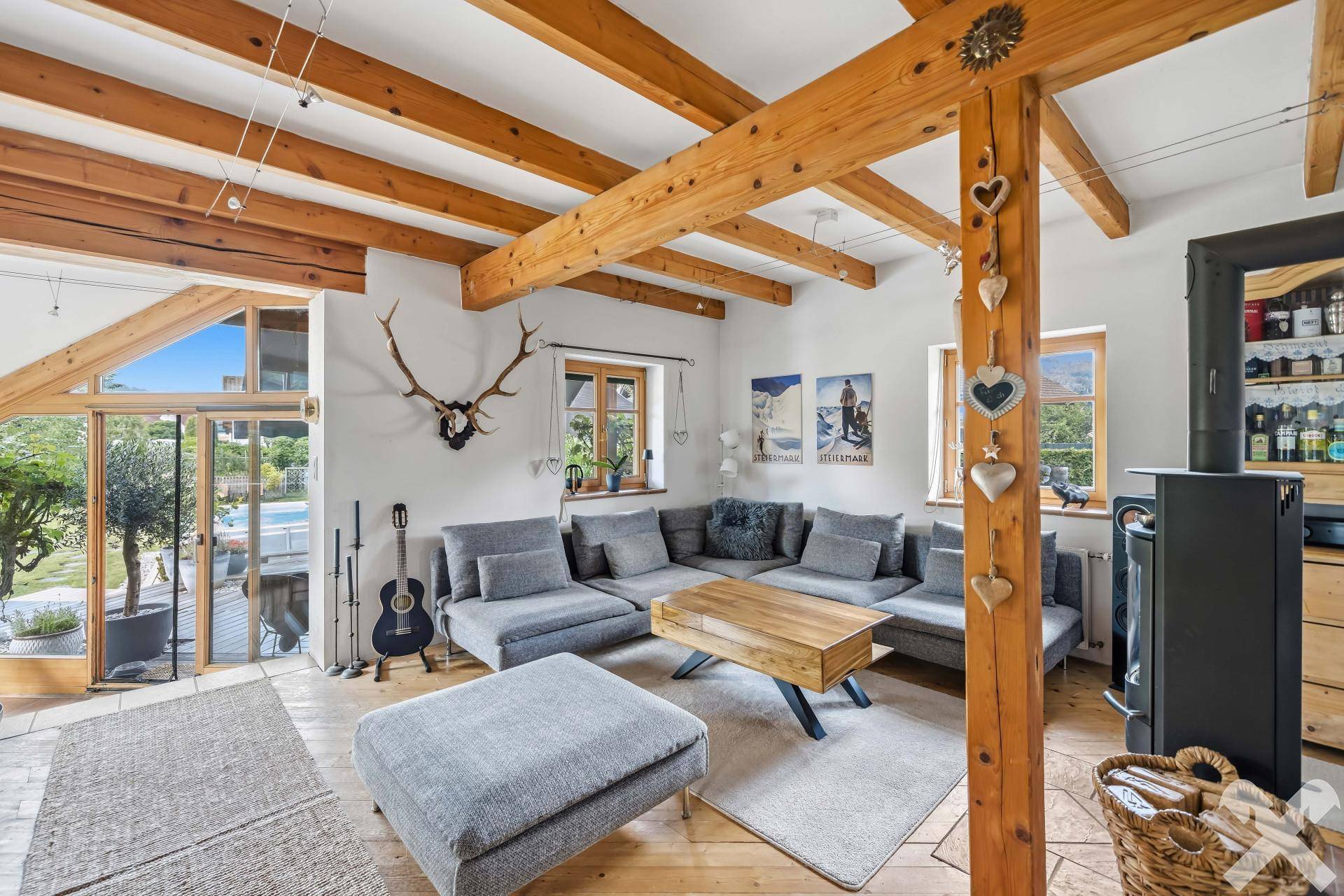 Helles Wohnzimmer mit Holzbalken, gemütlicher Sitzecke und Zugang zur Terrasse.