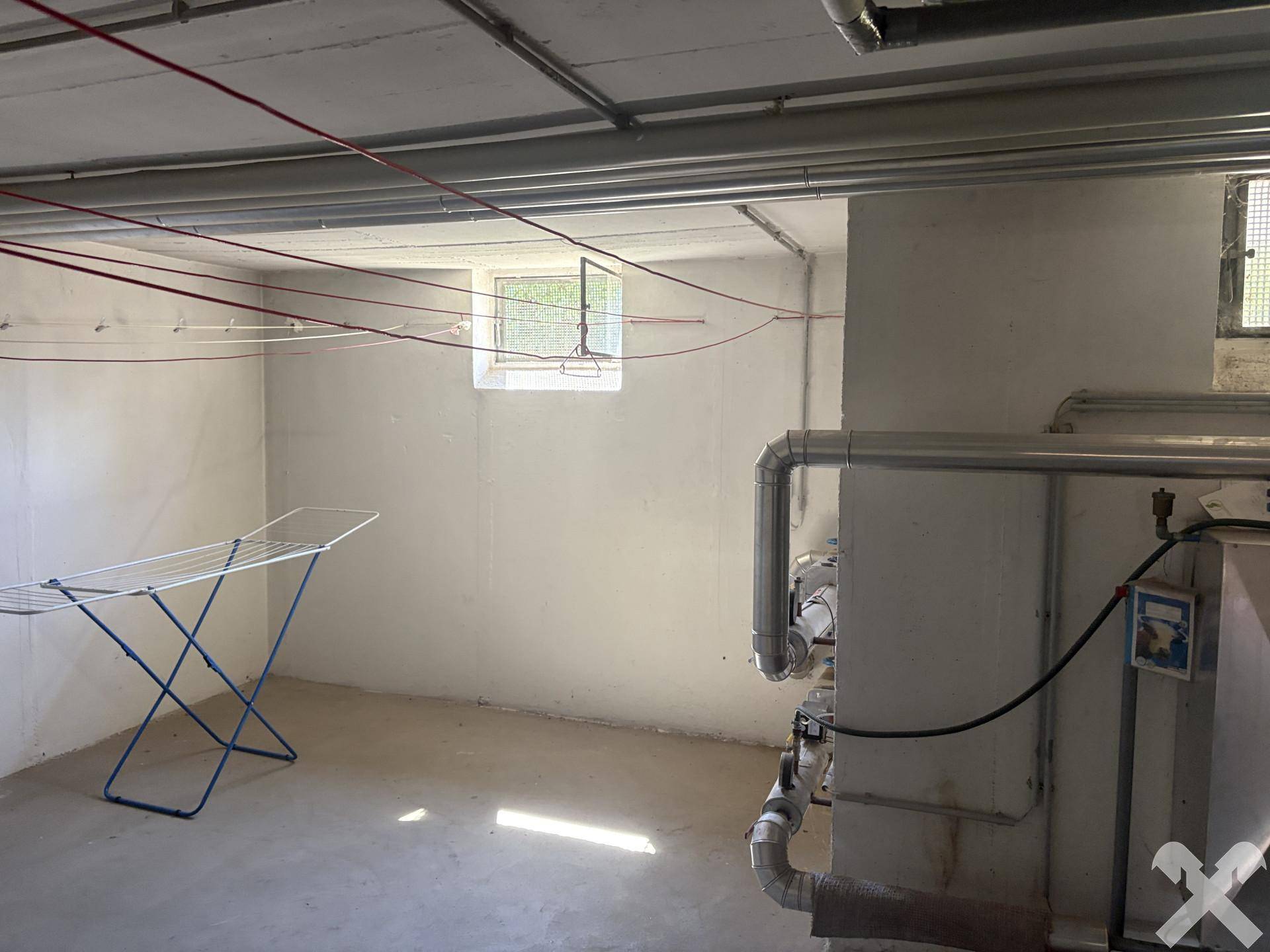Heller Hauswirtschaftsraum im Keller mit Wäscheständer und sichtbaren Installationen, funktional eingerichtet.