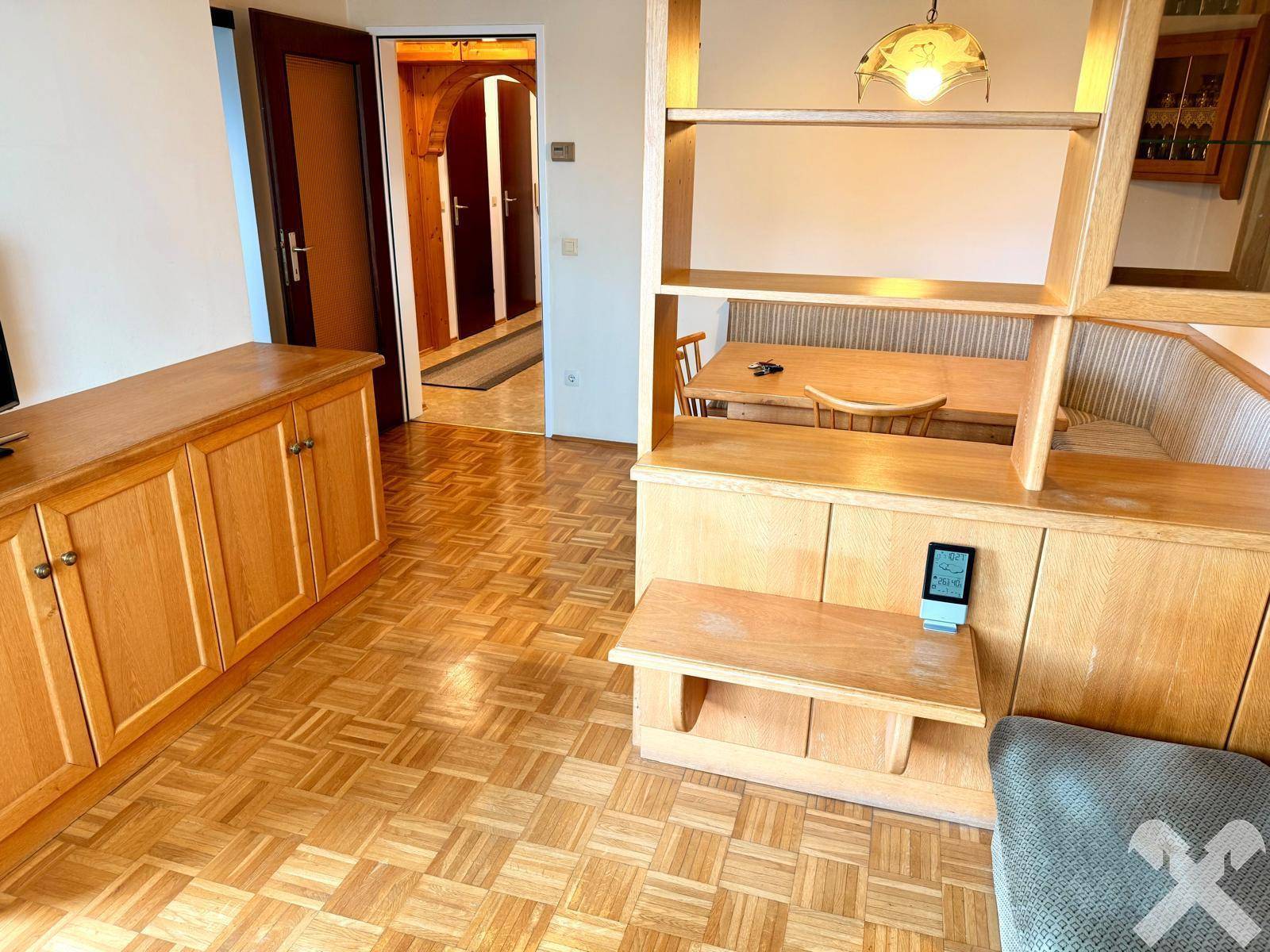 Wohn- und Essbereich mit Holzmöbeln, Parkettboden und einem Durchgang zum Flur in traditionellem Stil.