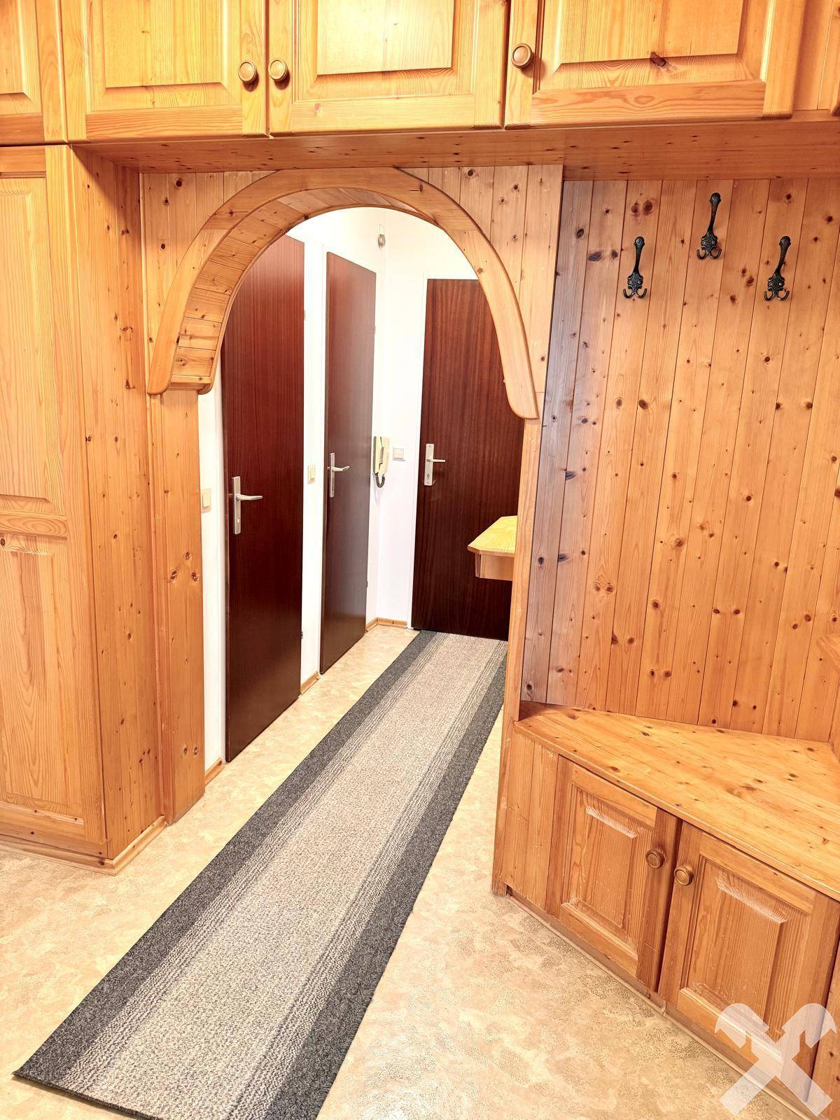 Flur mit holzvertäfelten Wänden, Einbauschränken und einem dekorativen Holzbogen, traditionell gestaltet.