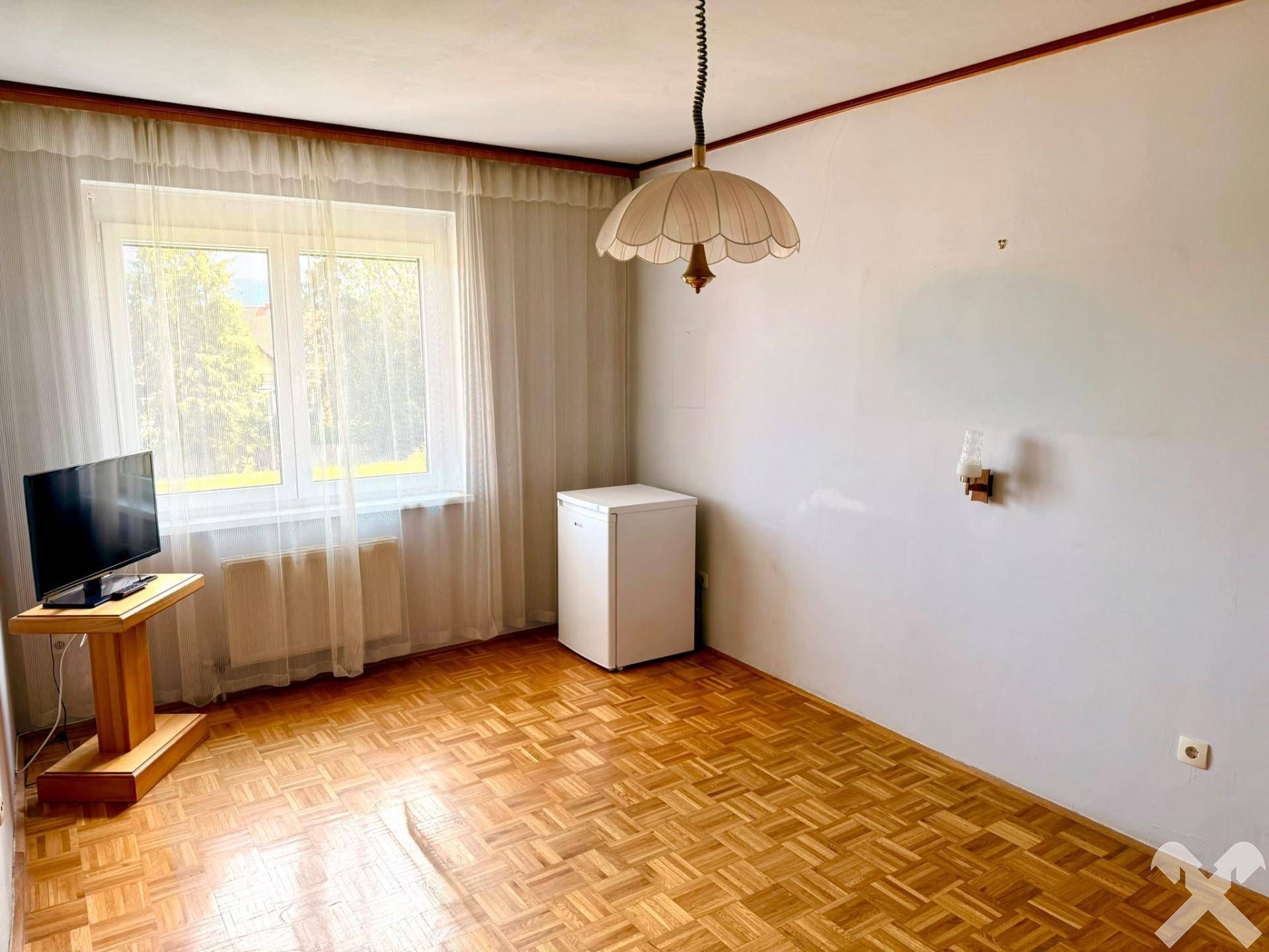 Helles Zimmer mit Parkettboden, großem Fenster und einem kleinen Kühlschrank, gut gepflegt.