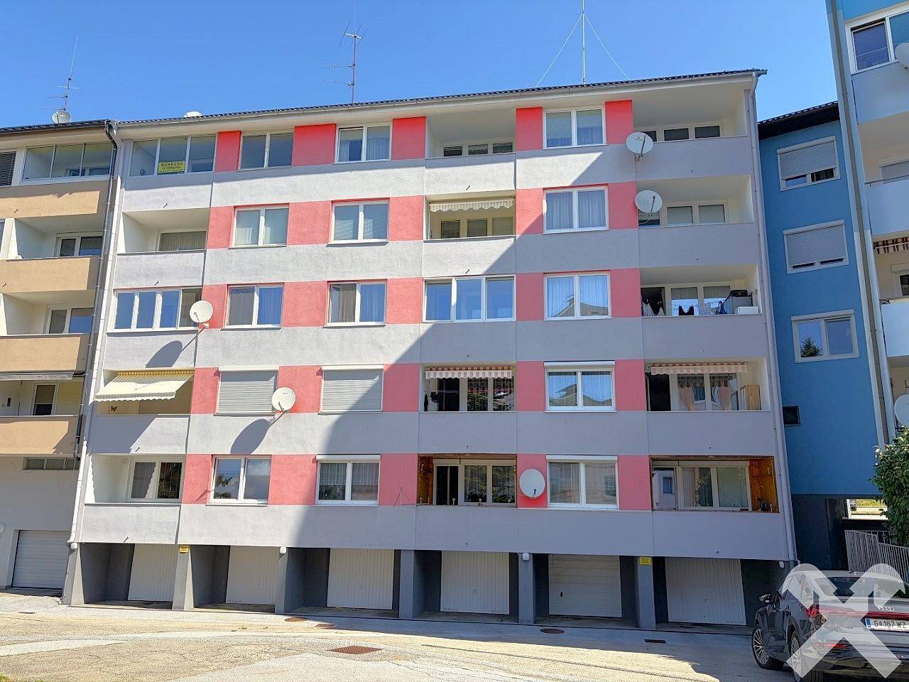 Nahaufnahme der farbigen Fassade eines Mehrfamilienhauses mit Balkonen und Satellitenschüsseln.