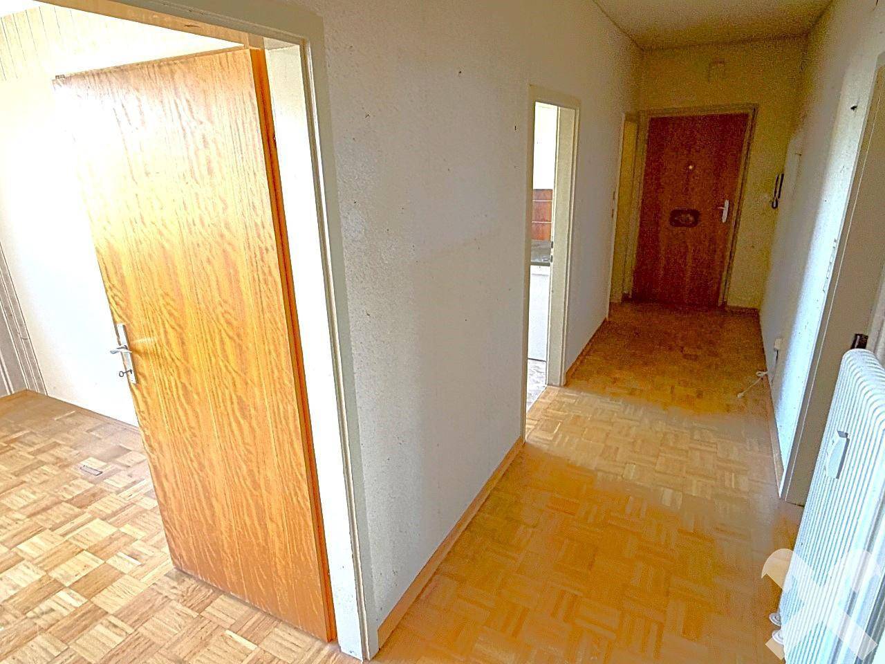 Flur mit Parkettboden und Holztüren, der Zugang zu verschiedenen Räumen der Wohnung bietet.
