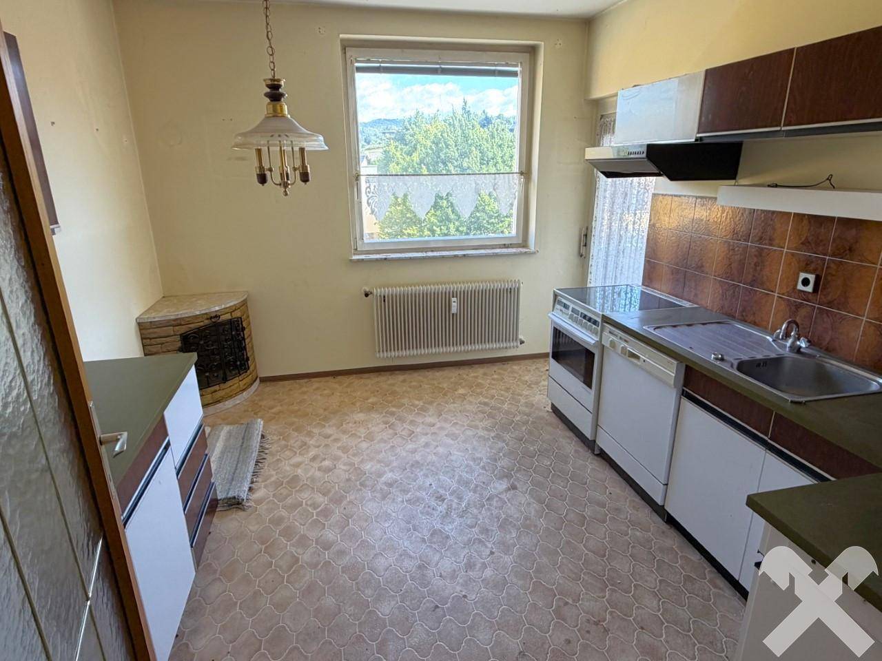 Küche mit älterer Einbauküche, Linoleumboden und Fenster mit Blick ins Grüne.