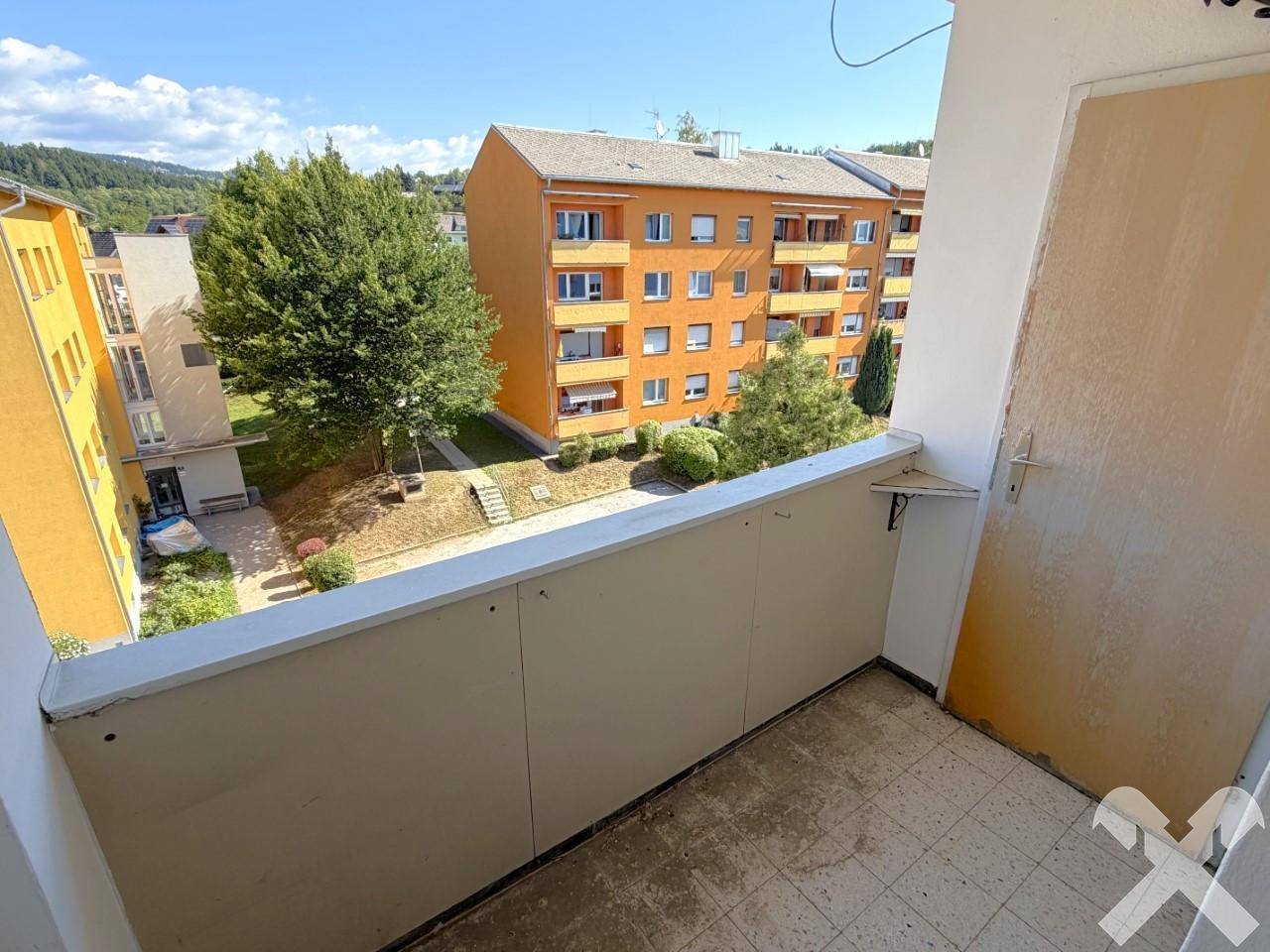 Balkon mit Blick auf die umliegenden Gebäude und die grüne Hügellandschaft.