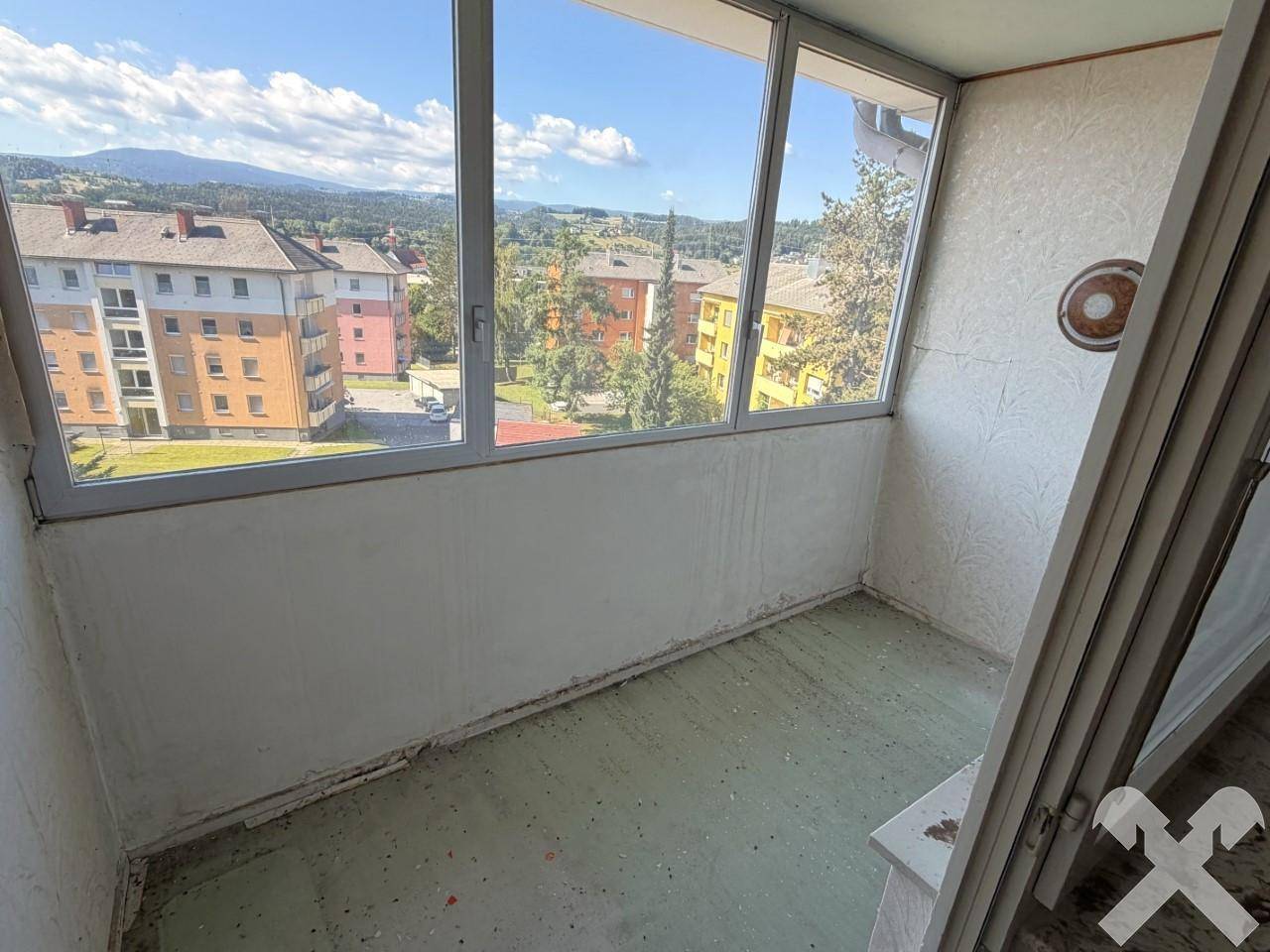 Verglaster Balkon mit großen Fenstern und weitem Blick über die Stadt und Landschaft.