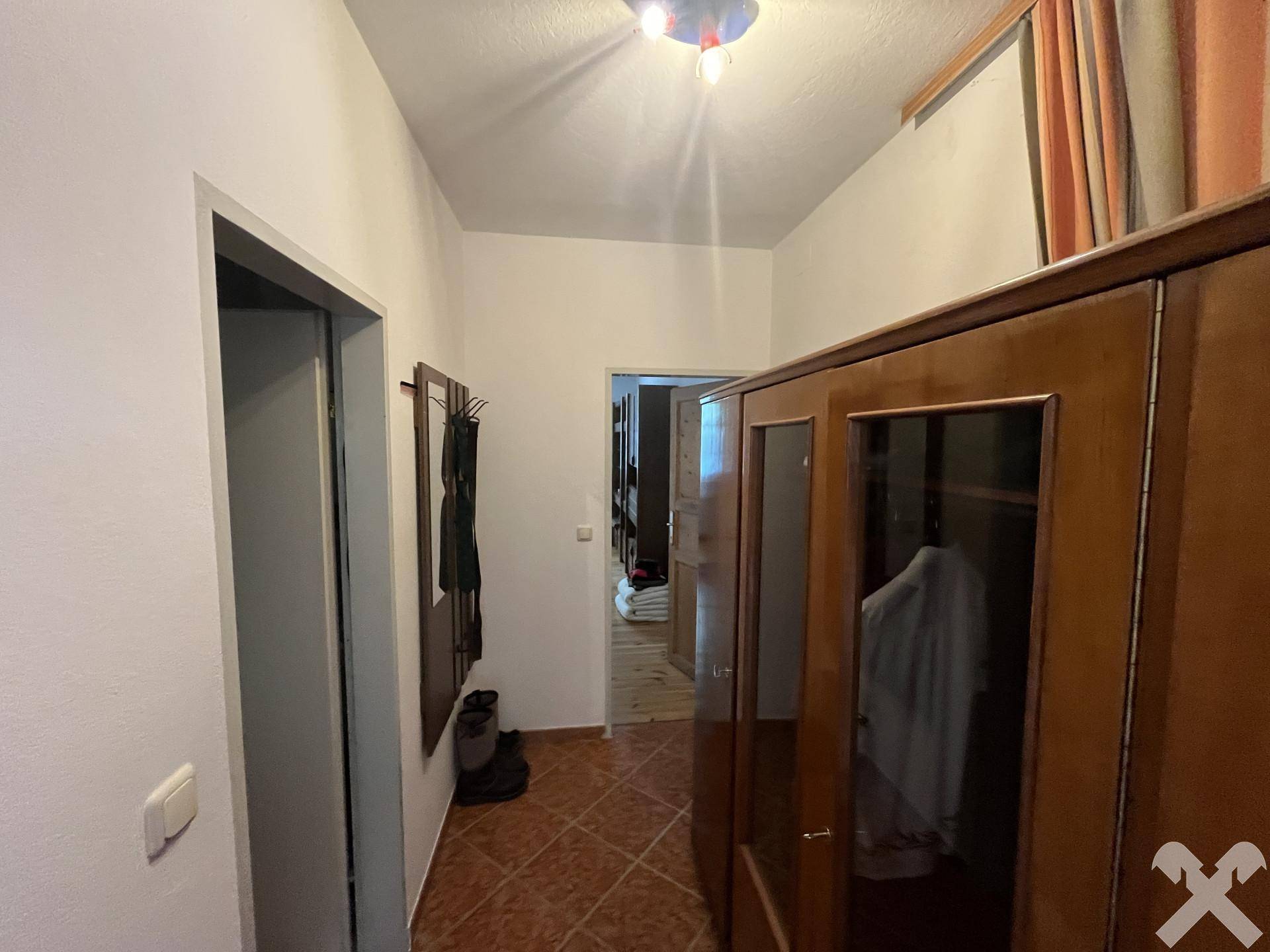 Flur mit Holzschrank und gefliestem Boden, der zu weiteren Räumen führt.