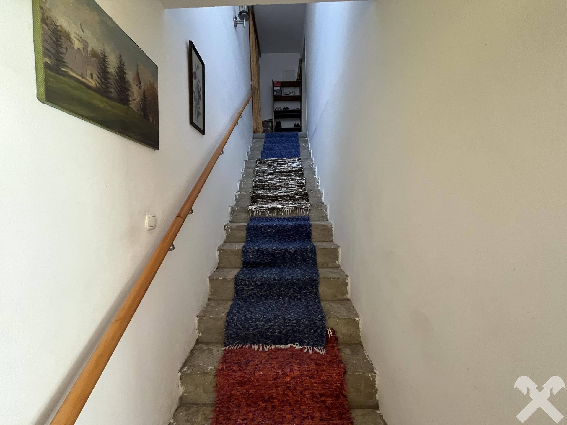 Treppenhaus mit Teppichläufern und Holzgeländer, das in die obere Etage führt.