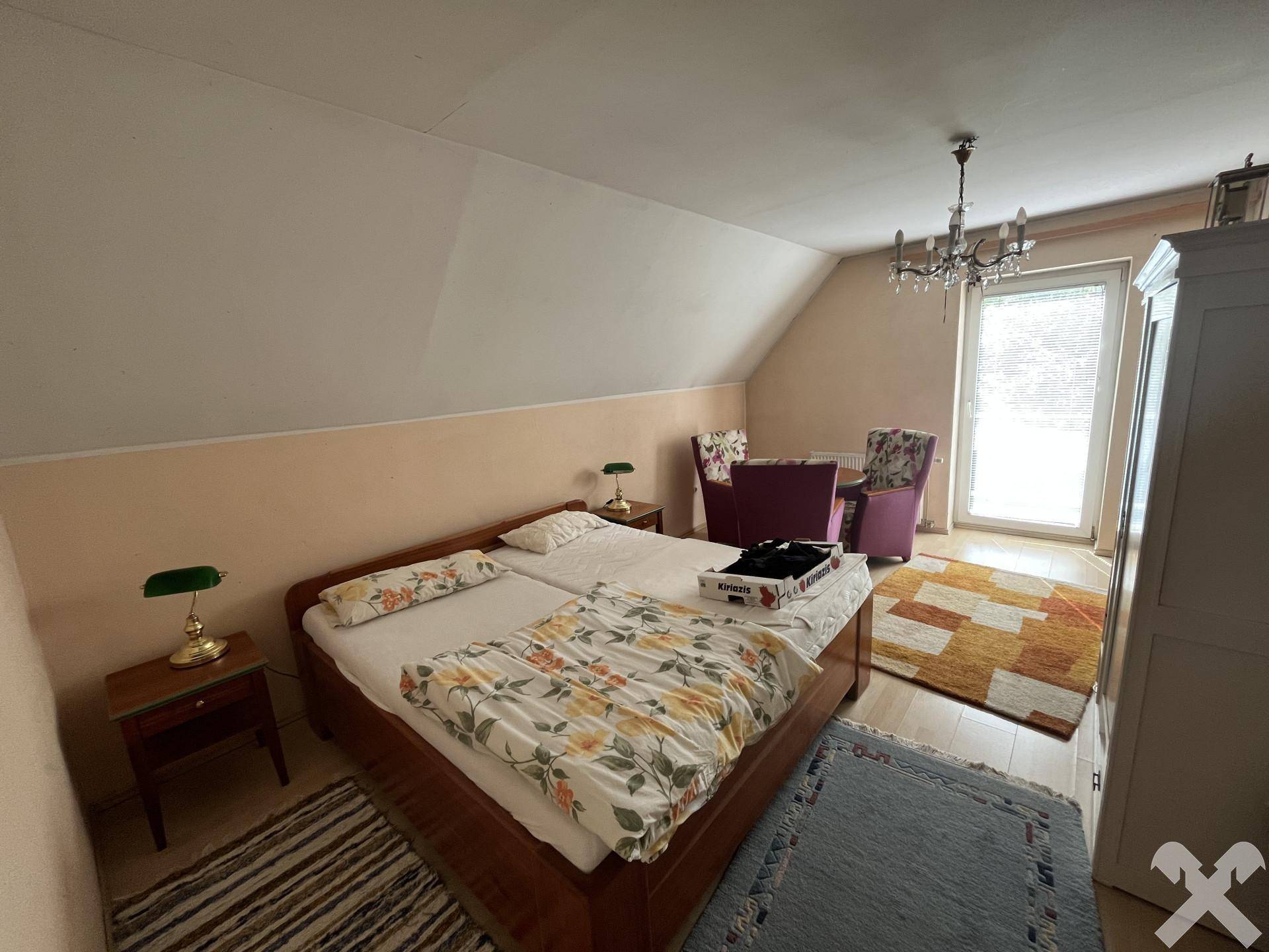 Schlafzimmer im Dachgeschoss mit Doppelbett, Schrank und Zugang zu einem Balkon oder einer Terrasse.