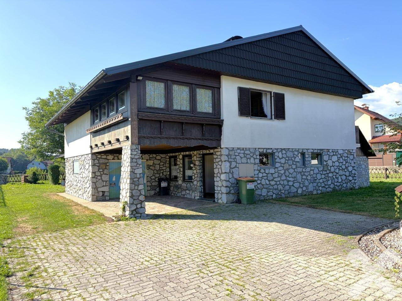 Vorderansicht des Hauses mit gepflasterter Auffahrt und überdachtem Eingangsbereich.