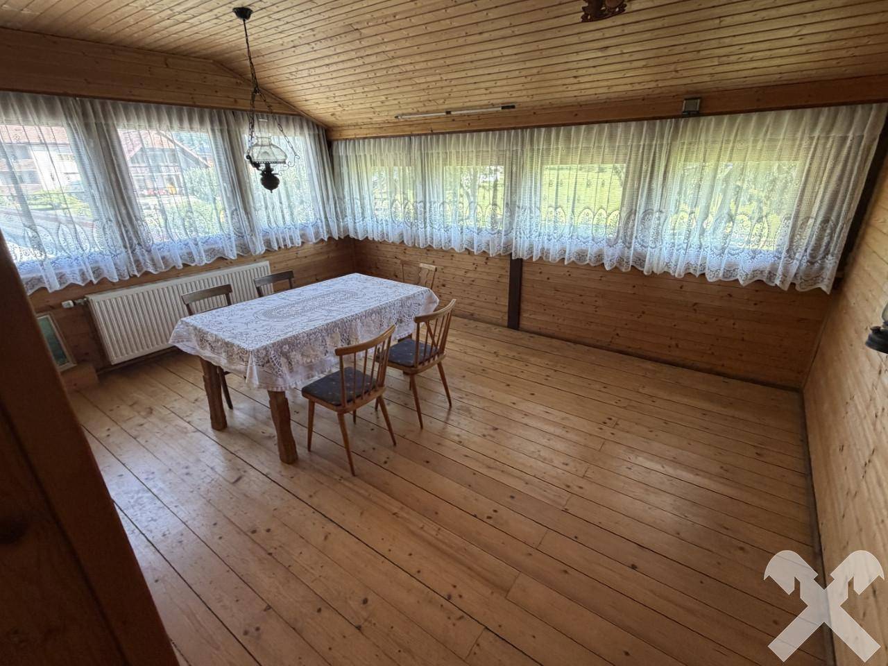 Gemütlicher Wintergarten mit Holzboden, Esstisch und vielen Fenstern für viel Licht.