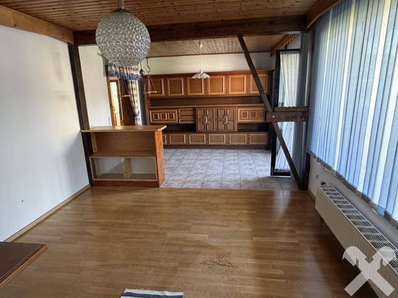 Offener Wohnbereich mit Holzboden, Einbauschränken und Blick auf den Balkon.