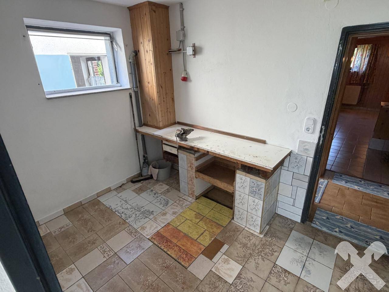 Kleiner Hauswirtschaftsraum mit Arbeitsplatte, Spüle und Fenster.