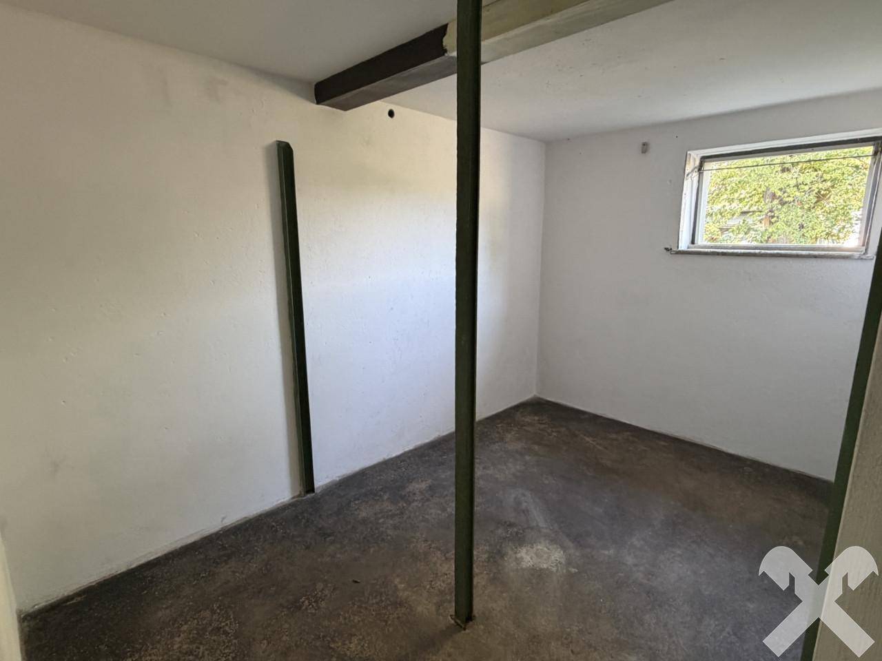 Unfertiger Kellerraum mit Betonboden und kleinem Fenster.