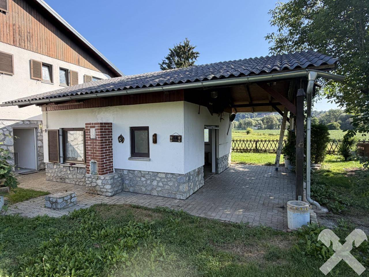 Überdachte Terrasse mit Grillplatz und Blick auf die umliegende Landschaft.