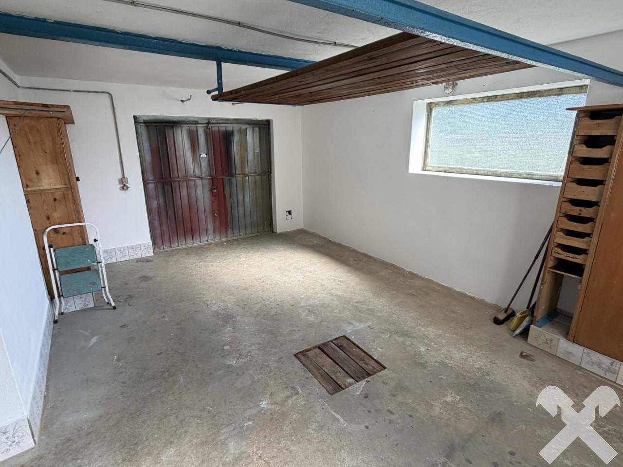 Geräumige Garage mit Betonboden, Doppeltor und Fenster.