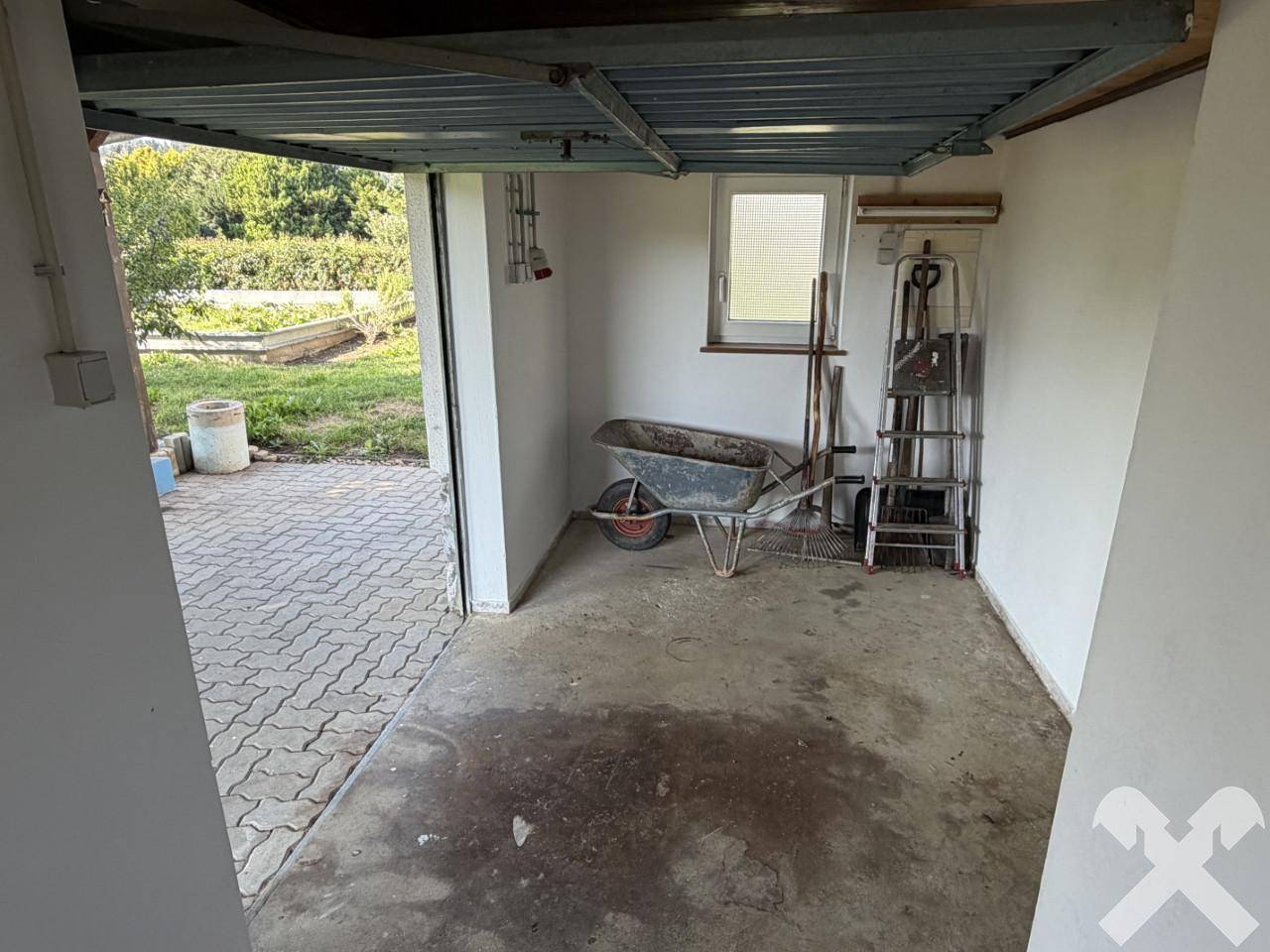 Kleiner Abstellraum oder Werkstatt mit Betonboden und Zugang zum Außenbereich.