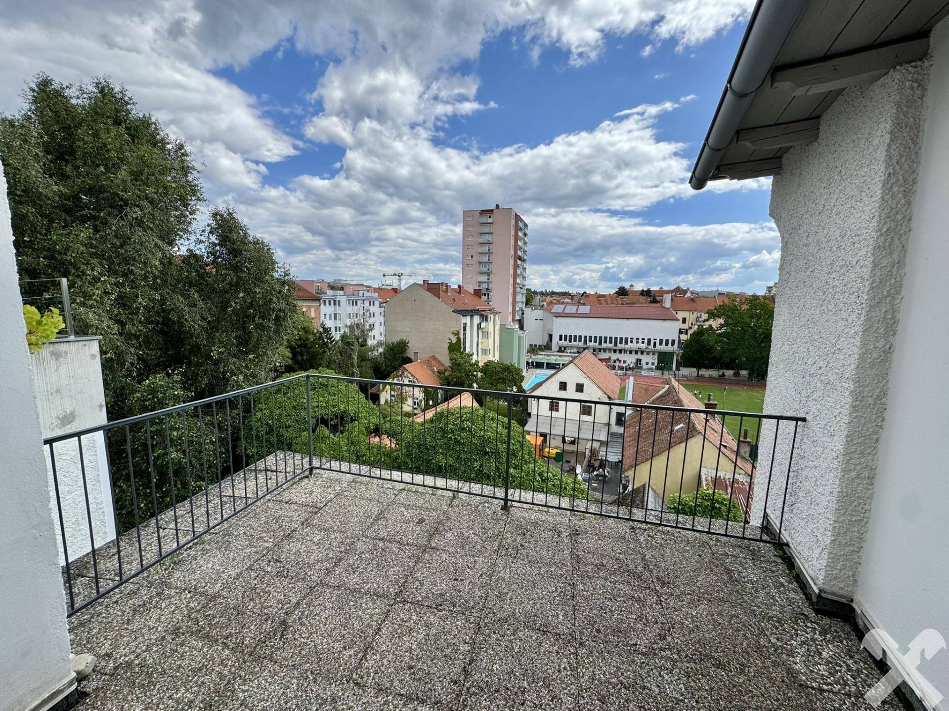 Geräumige Terrasse mit Fliesenboden und weitem Blick über die Stadt und umliegende Gebäude.