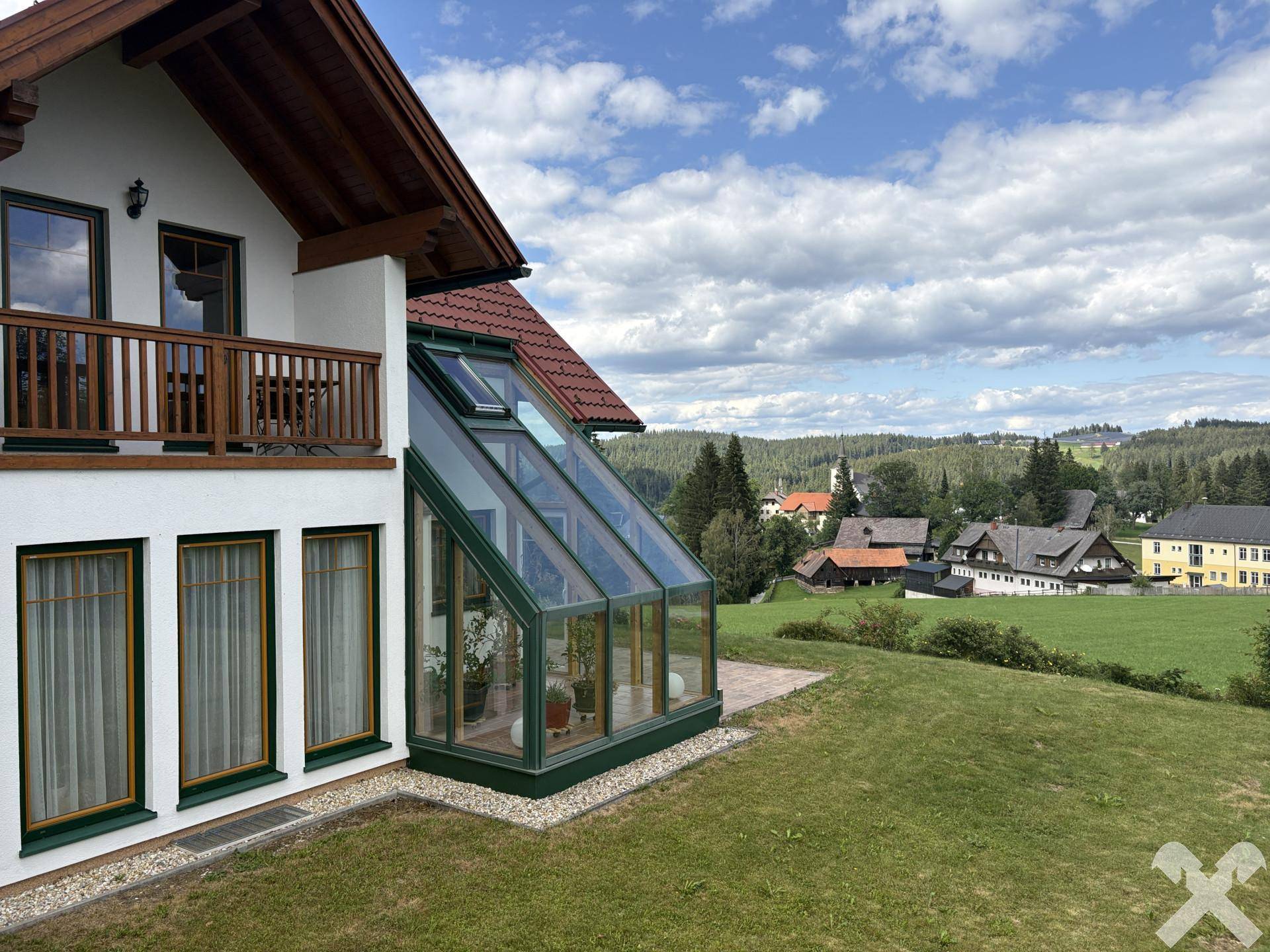 Hausfassade mit verglastem Wintergarten und weitem Blick über die ländliche Umgebung.