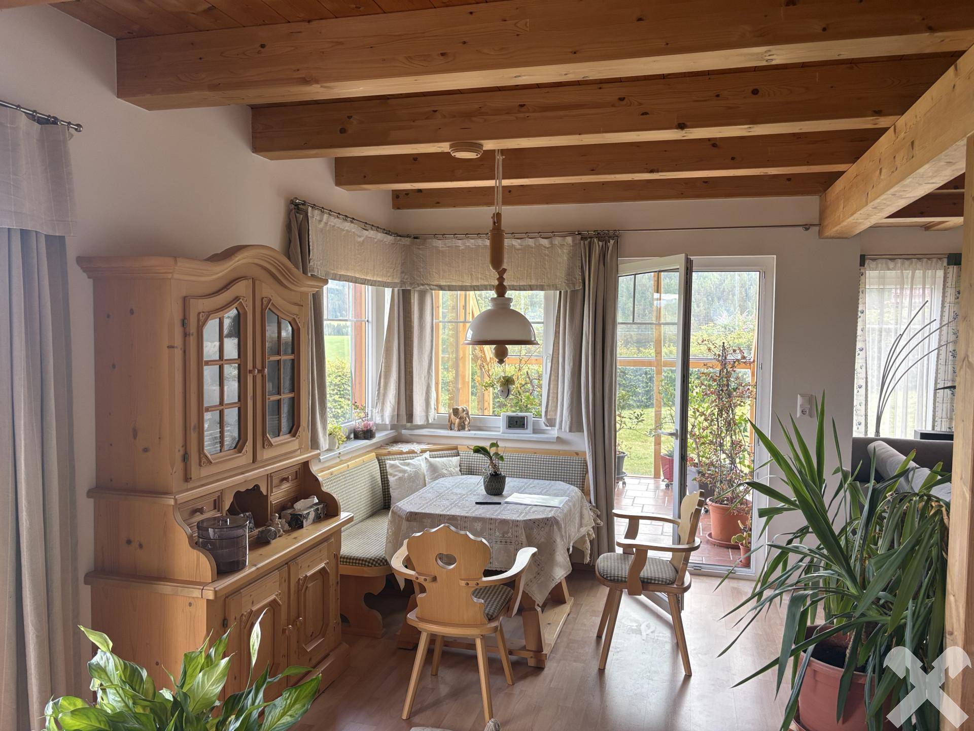 Traditioneller Essbereich mit Eckbank, Holzmöbeln und Blick in den Garten durch große Fenster.
