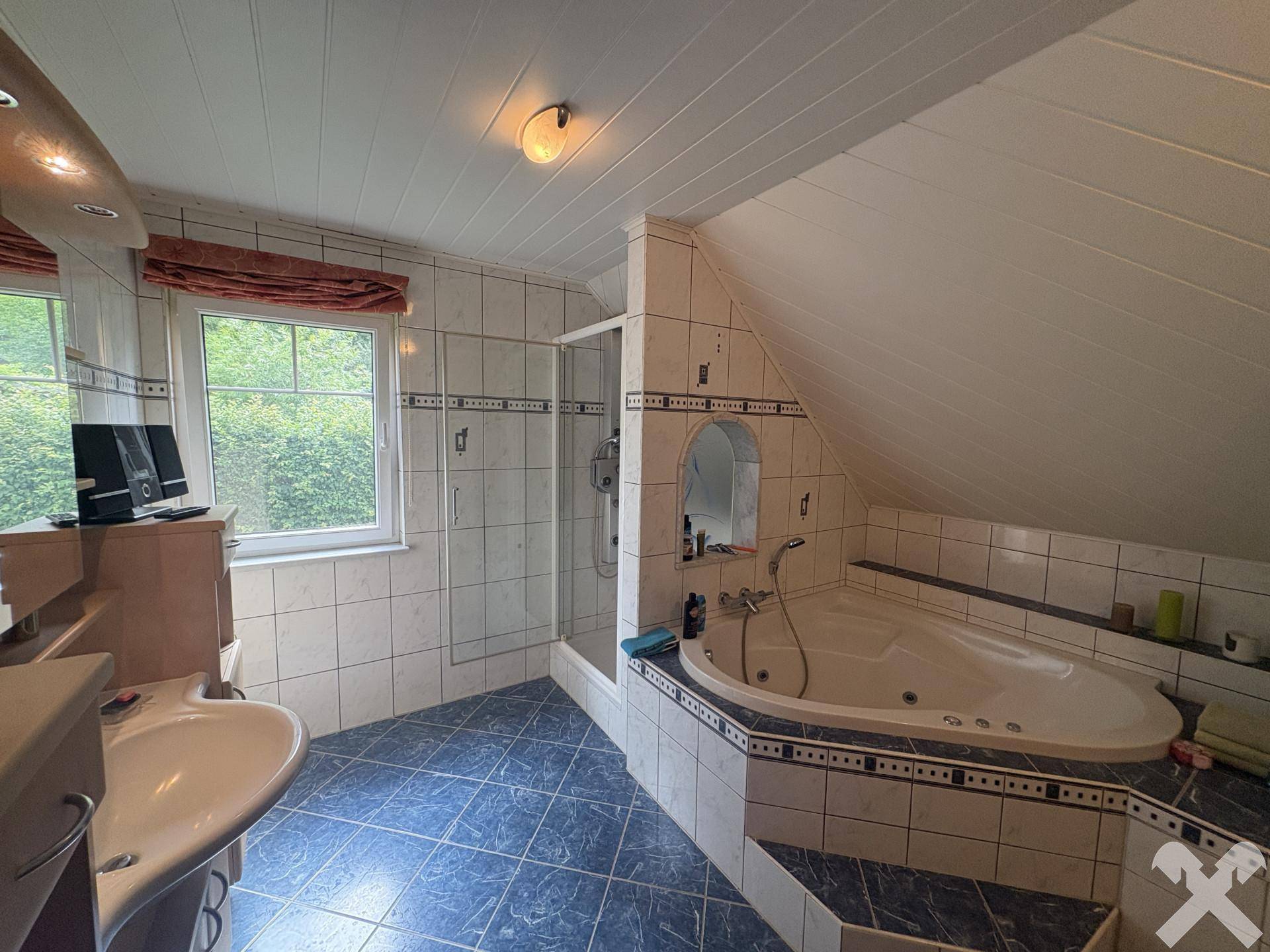 Geräumiges Badezimmer mit blauen Fliesen, Eckbadewanne mit Whirlpoolfunktion und separater Dusche.