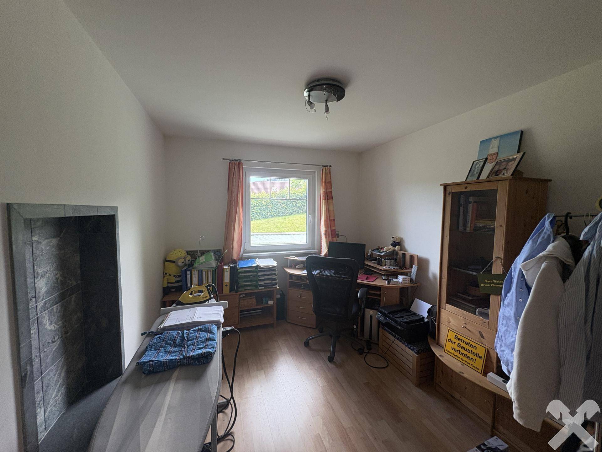 Helles Arbeitszimmer mit Laminatboden, Schreibtisch und Blick ins Grüne.