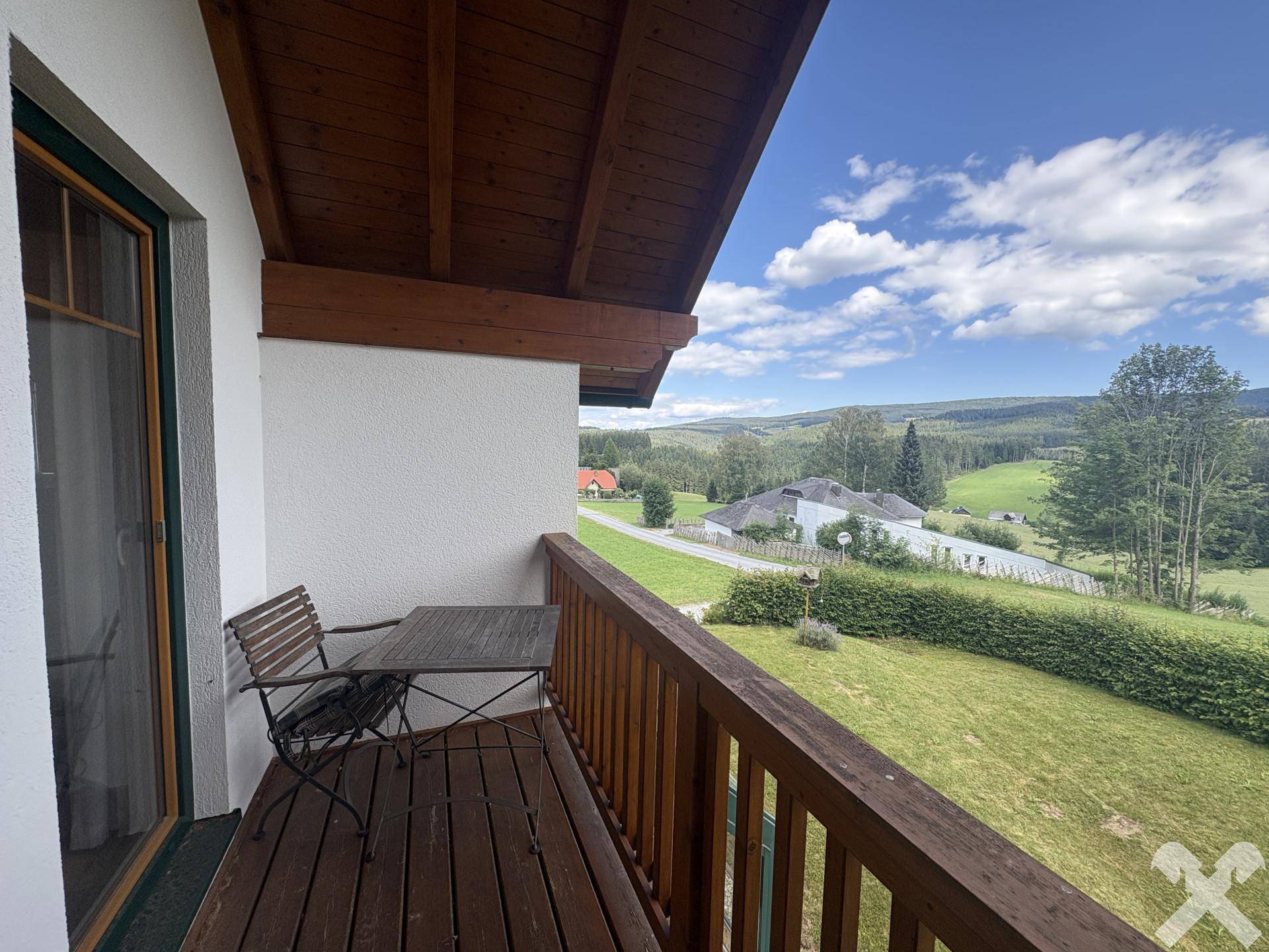 Gemütlicher Balkon mit Holzboden und Sitzgelegenheiten, ideal für den Blick ins Grüne.