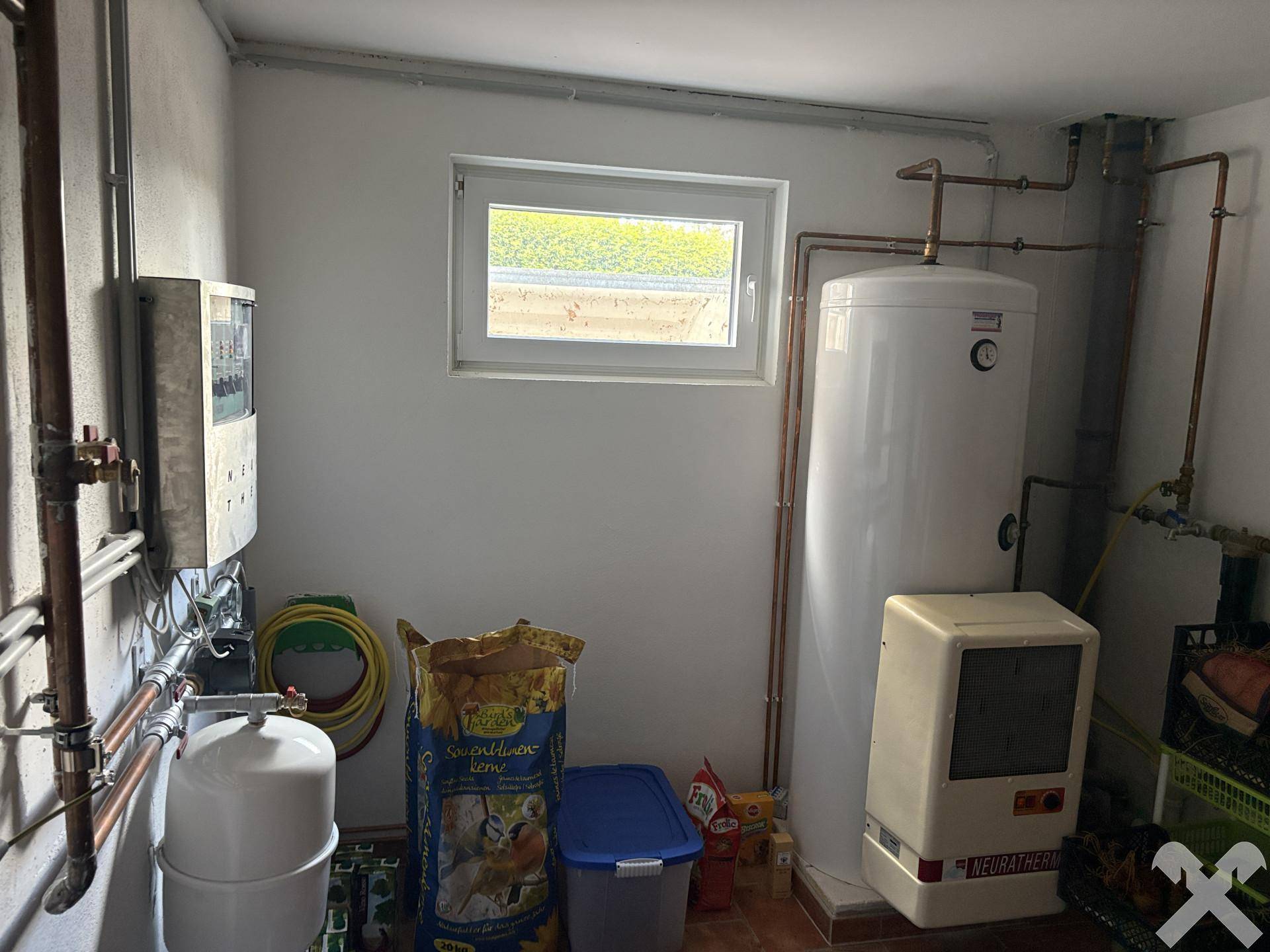 Hauswirtschaftsraum mit Warmwasserspeicher, Heizungsanlage und kleinem Fenster.