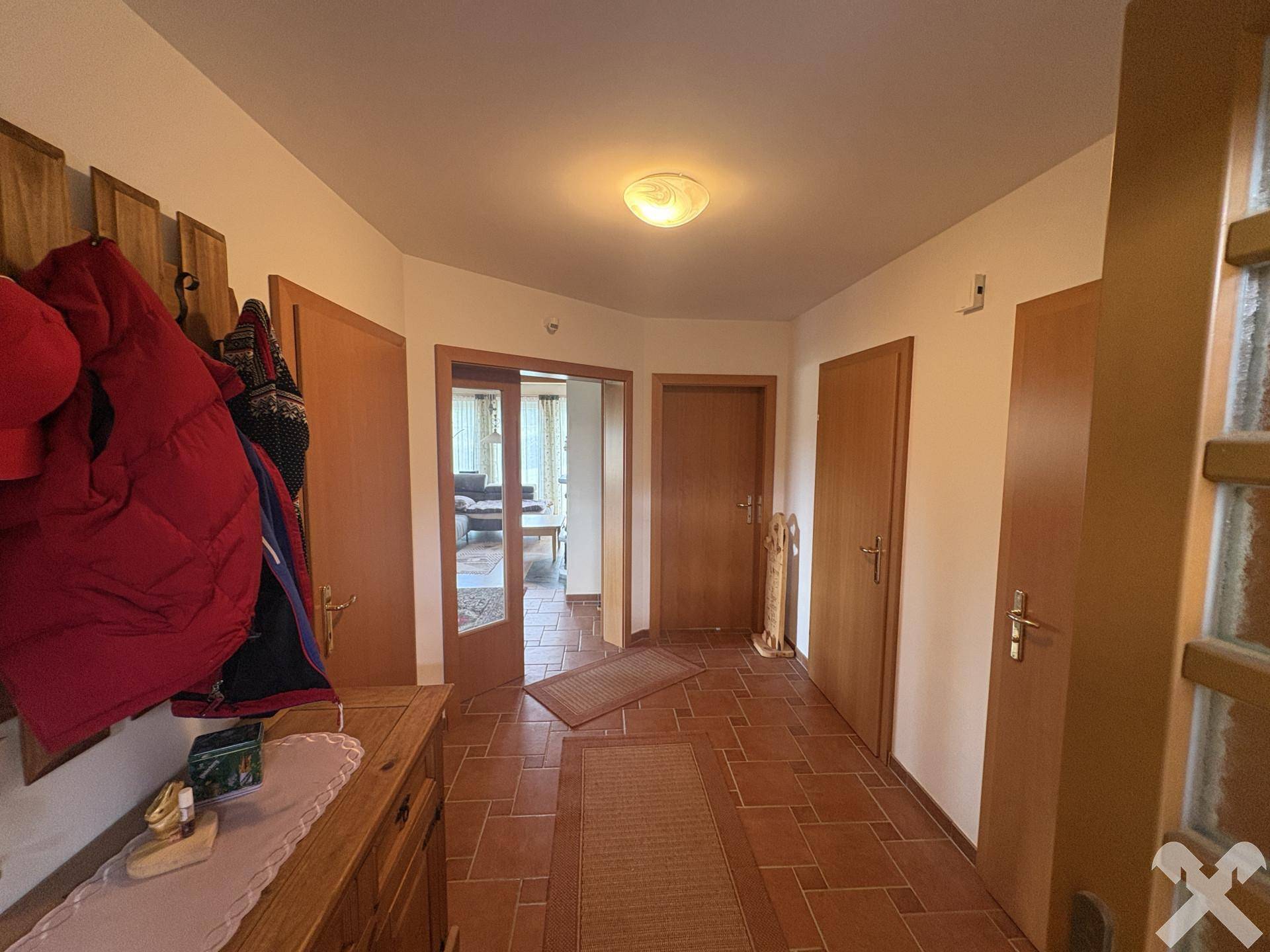 Geräumiger Flur mit Terrakotta-Fliesenboden, Holztüren und Garderobe.
