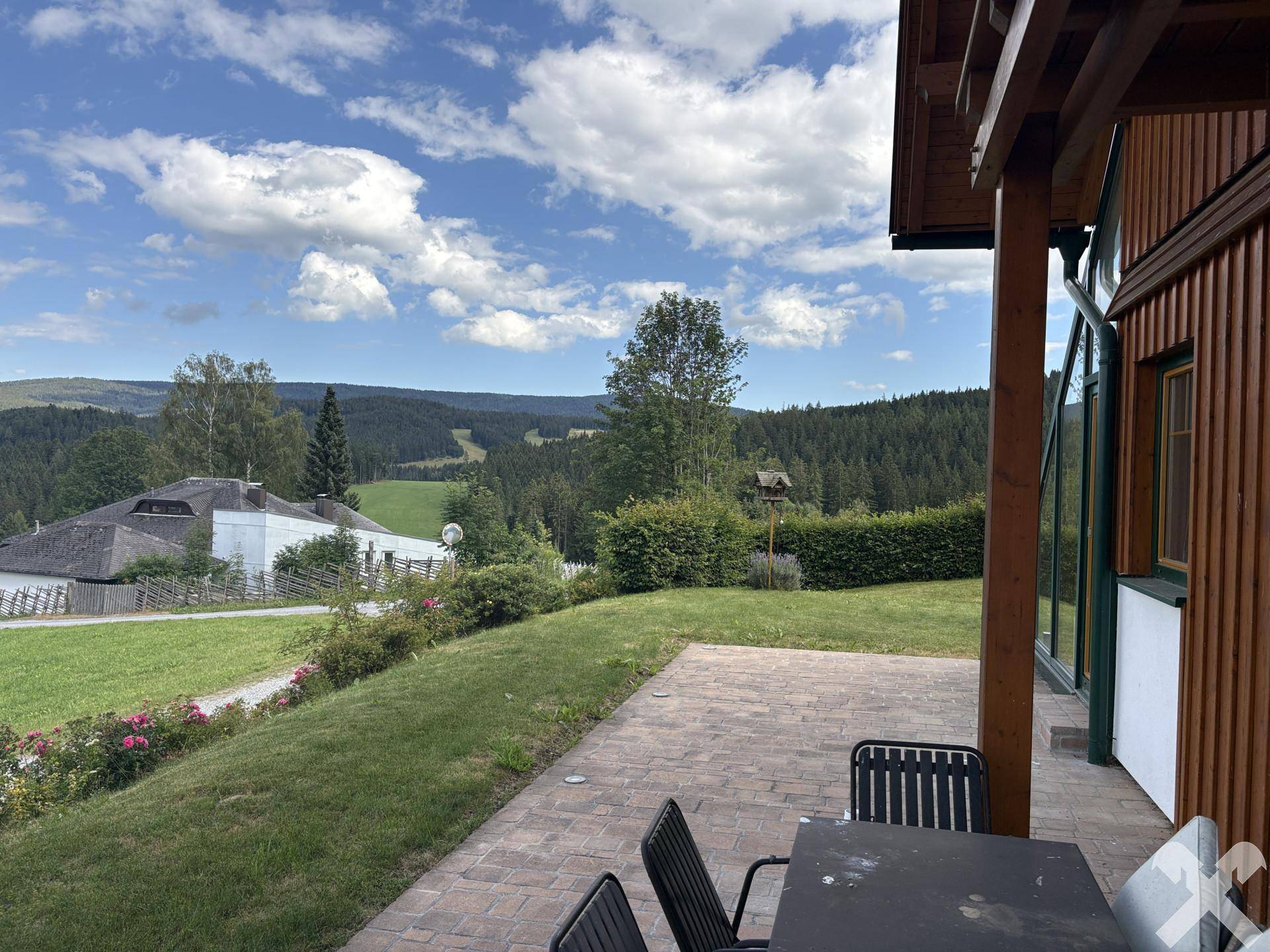Große gepflasterte Terrasse mit Sitzgelegenheiten und weitem Blick ins Grüne.
