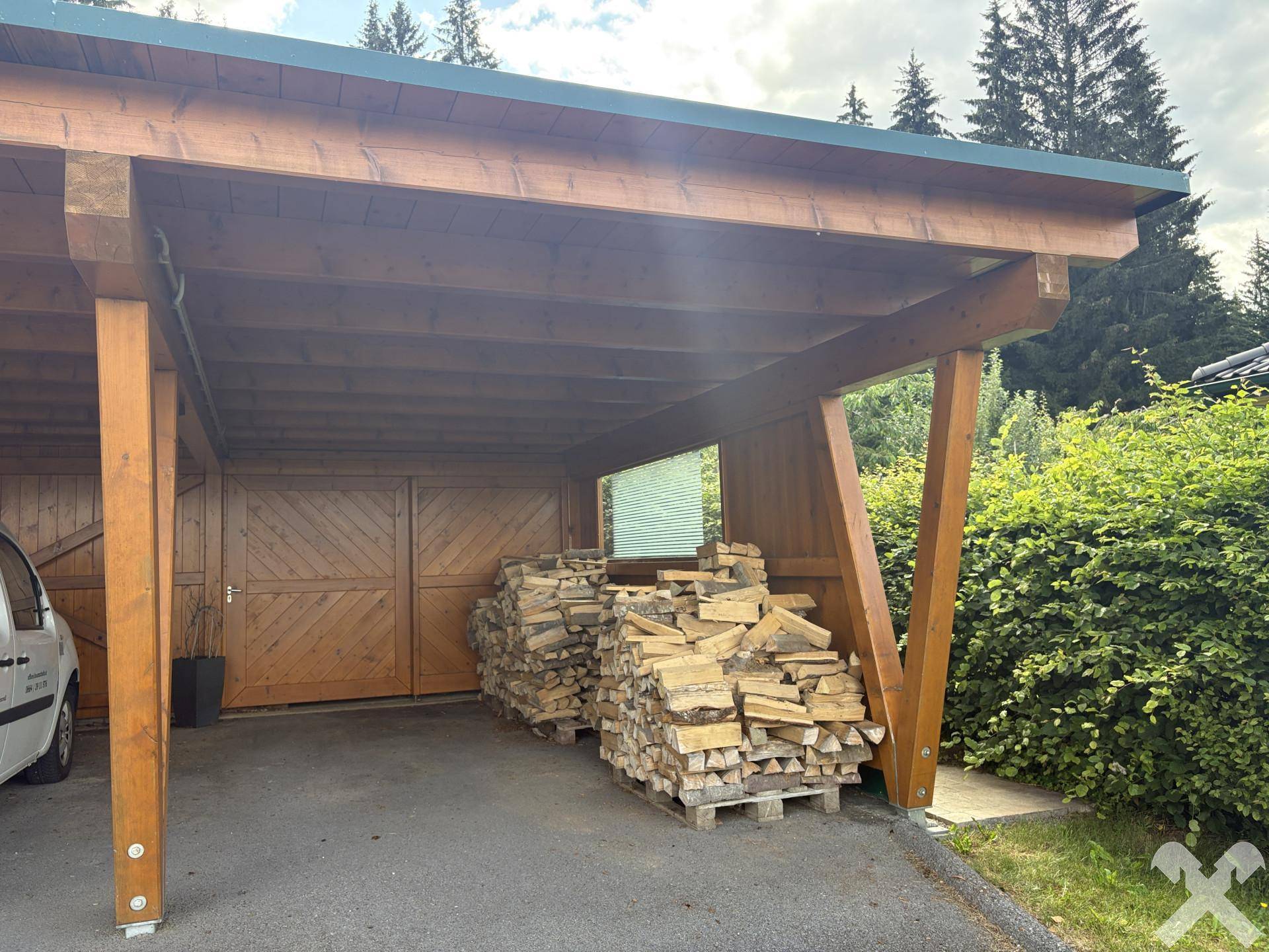 Geräumiger Holz-Carport mit Lagerplatz für Brennholz.