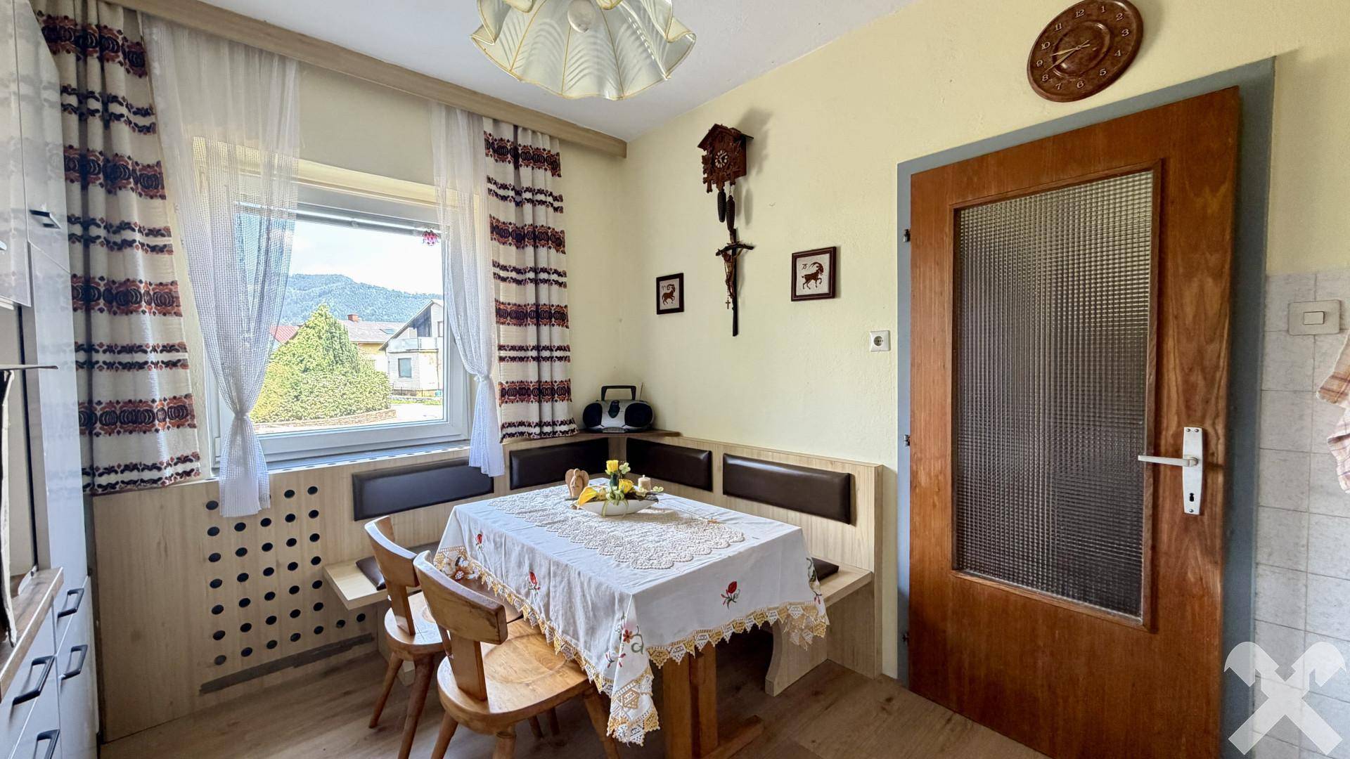 Gemütliche Essecke in der Küche mit Holztisch, Eckbank und Fensterblick ins Grüne.