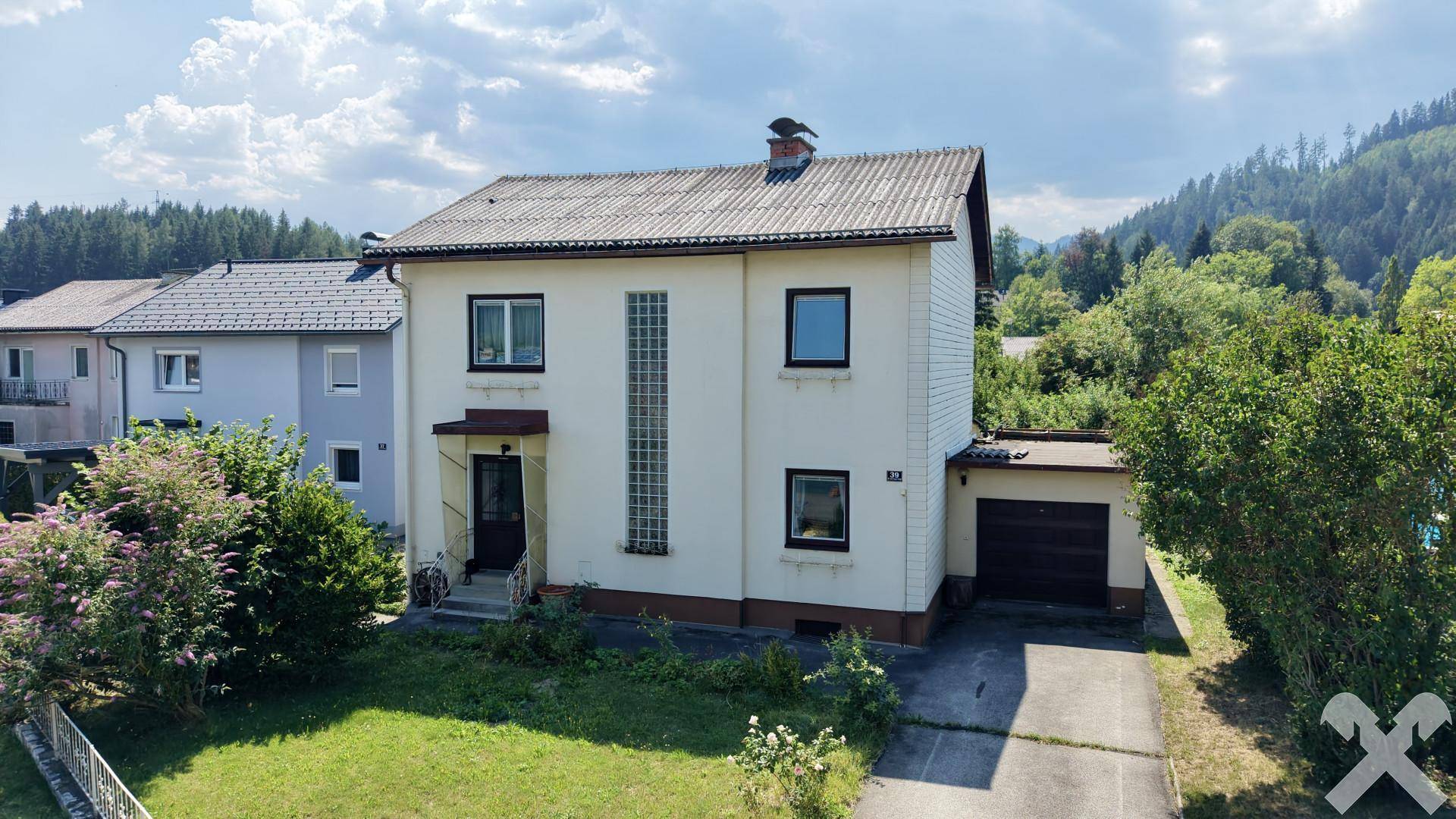 Vorderansicht des Hauses mit Vorgarten, Garage und Zufahrt in ländlicher Umgebung.