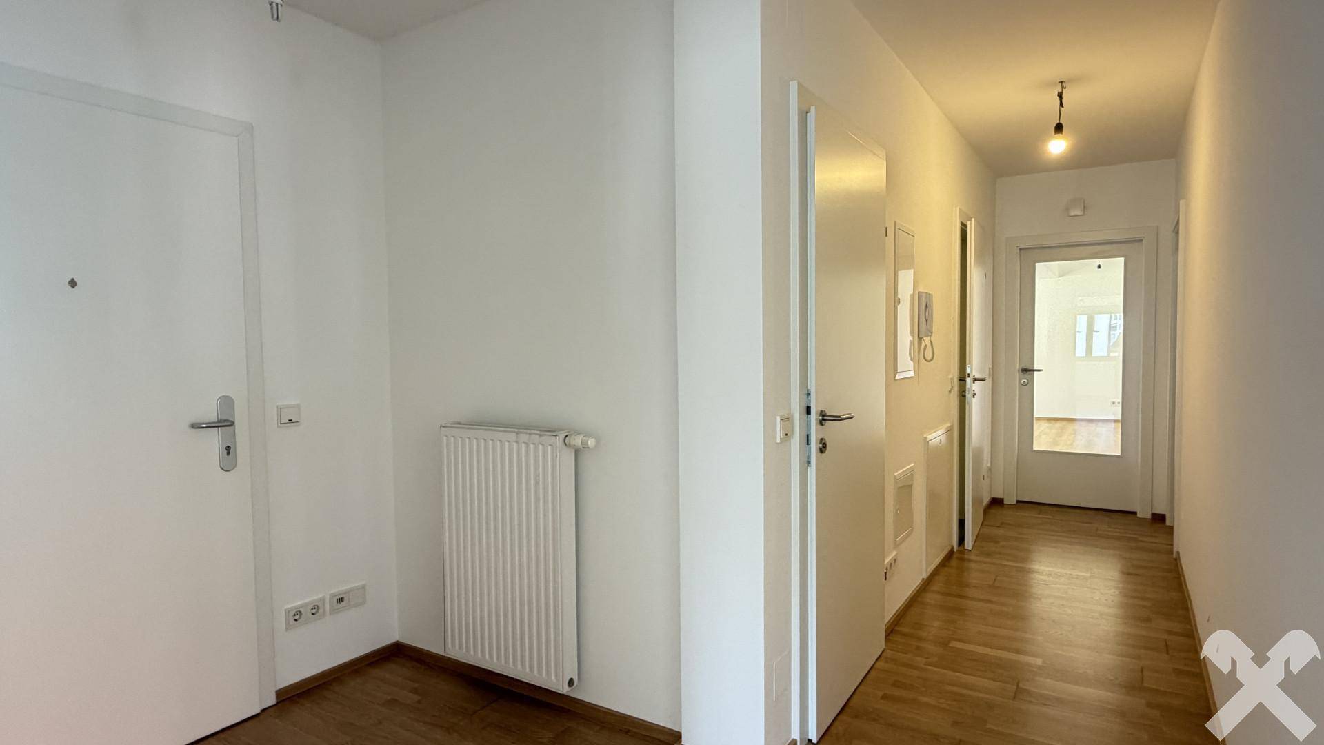 Heller Flur mit Laminatboden und weißen Wänden, der zu verschiedenen Räumen führt.