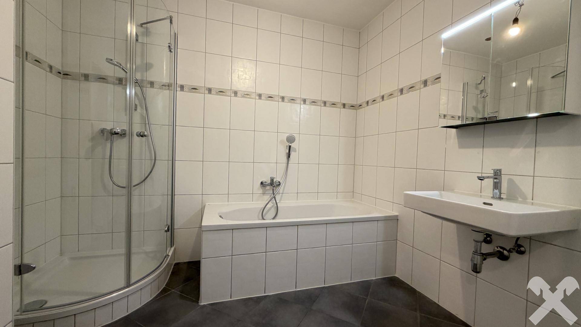 Modernes Badezimmer mit Badewanne, Duschkabine, Einzelwaschbecken und Fliesen an Wänden und Boden.