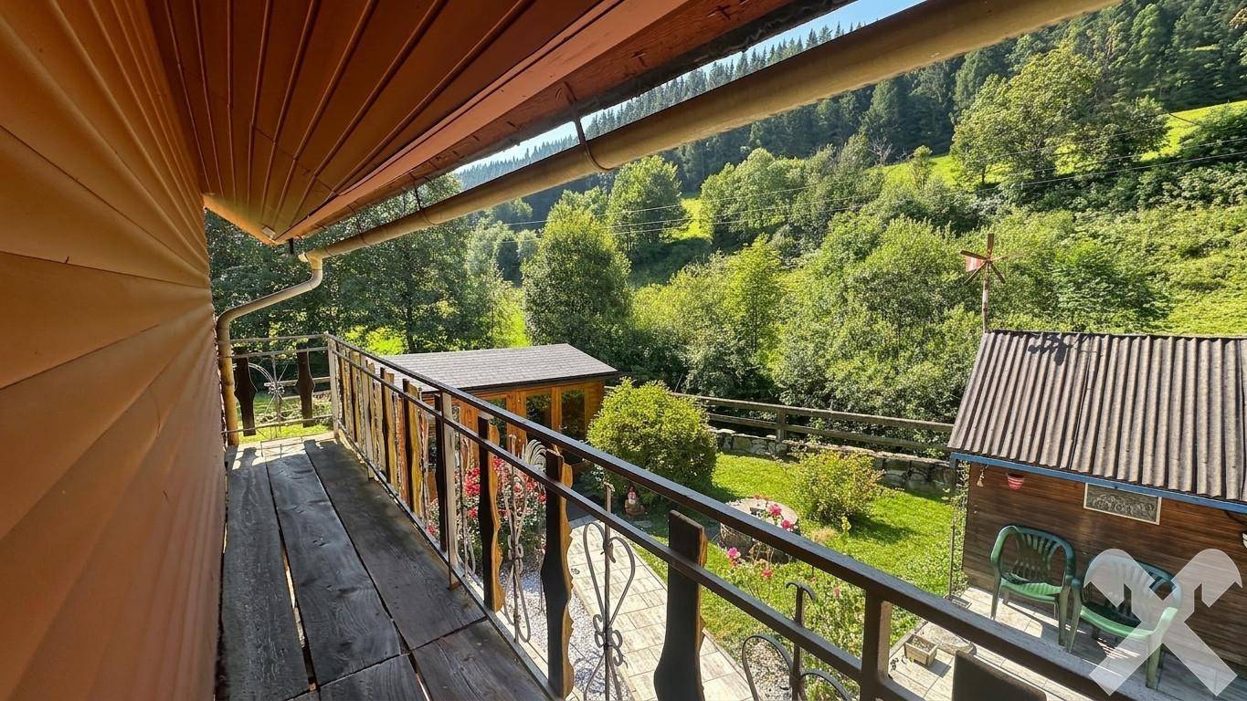 Blick vom Balkon auf die umliegende grüne Landschaft und die bewaldeten Hügel.
