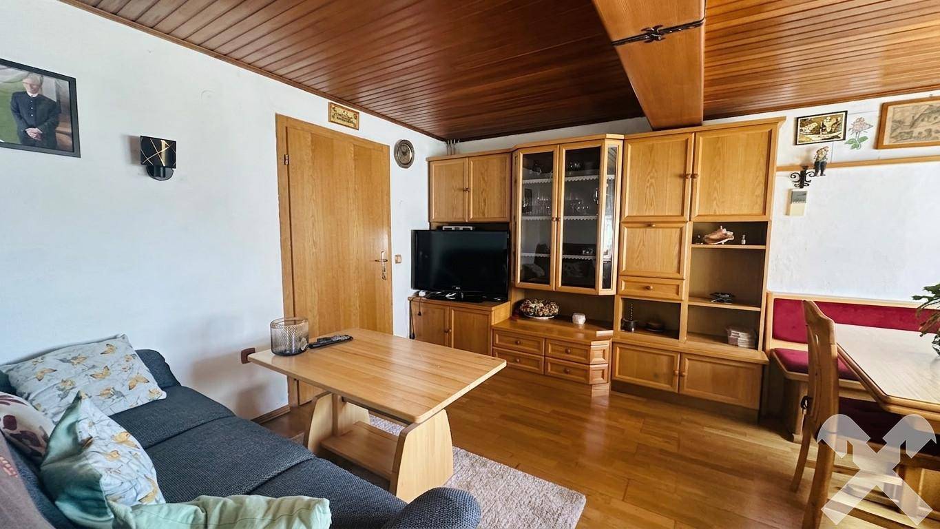 Gemütlicher Wohn-Essbereich mit Holzmöbeln, Holzboden und traditioneller Holzdecke.