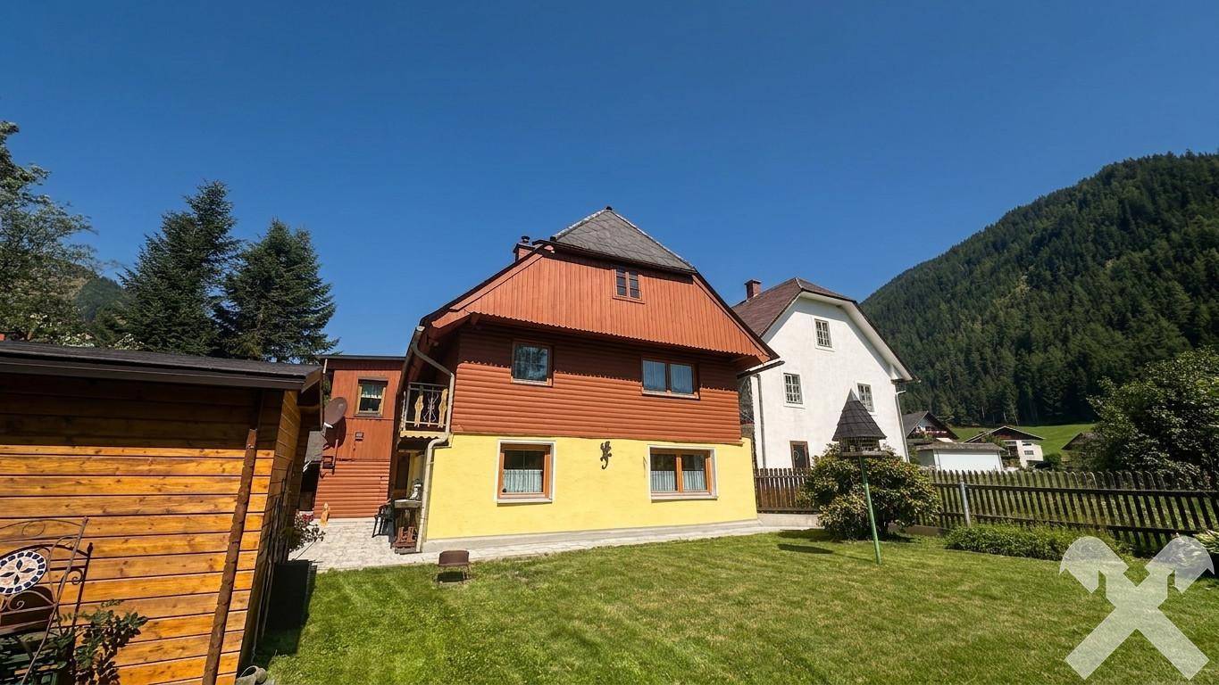 Weitläufiger Garten mit Rasenfläche und Blick auf das traditionelle Wohnhaus in sonniger Lage.