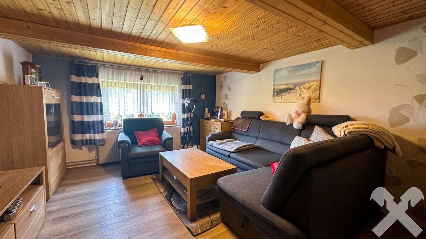 Gemütliches Wohnzimmer mit Sofa, Couchtisch und Holzdecke, ideal für entspannte Abende.
