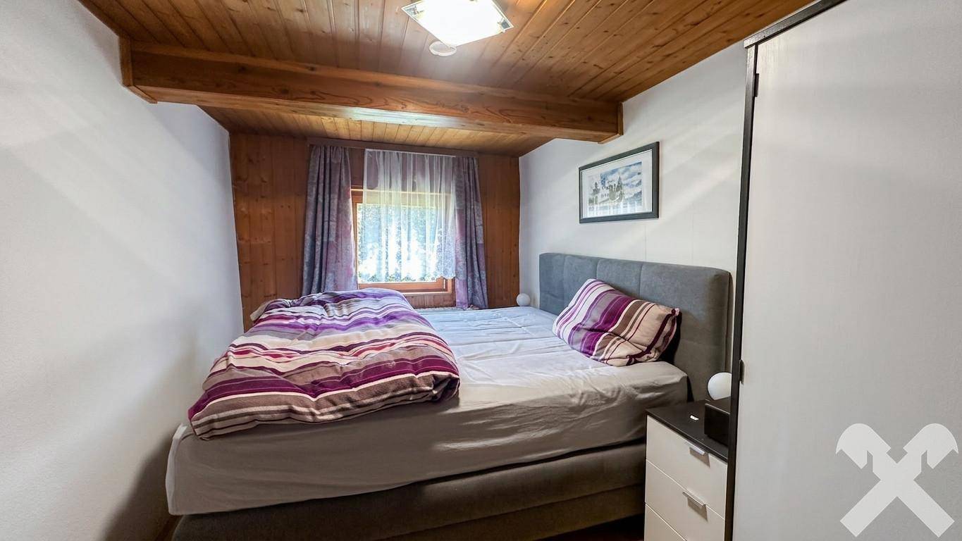 Schlafzimmer mit Doppelbett, Holzdecke und Kleiderschrank, bietet eine ruhige Rückzugsmöglichkeit.