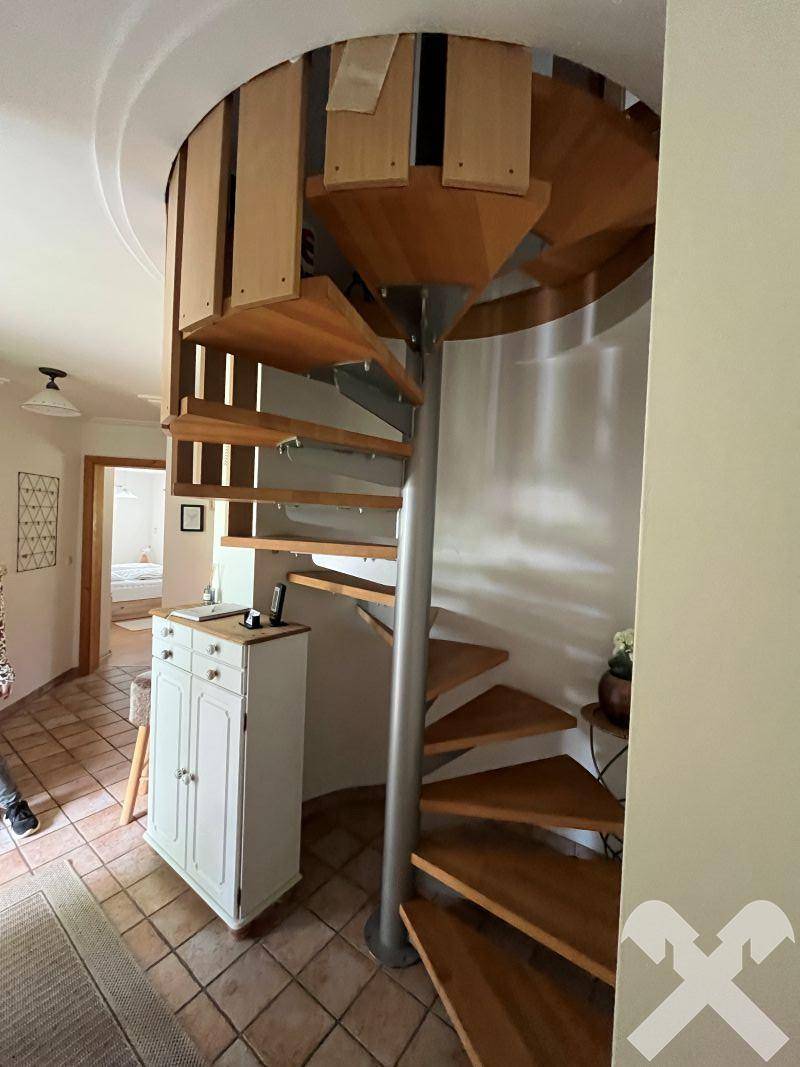 Heller Flur mit einer eleganten Holz-Wendeltreppe, die in die oberen Stockwerke führt.