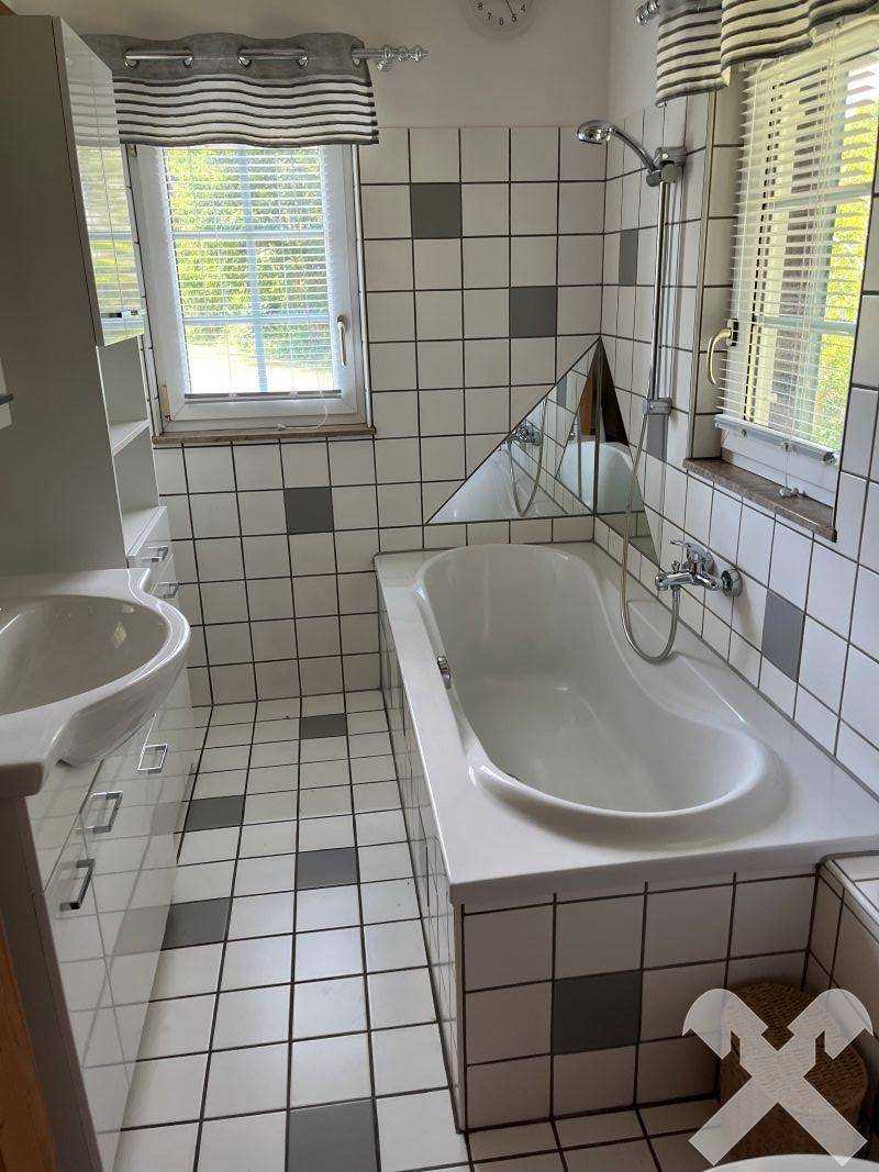 Badezimmer mit Badewanne, Waschbecken und schwarz-weiß gefliesten Wänden und Boden.