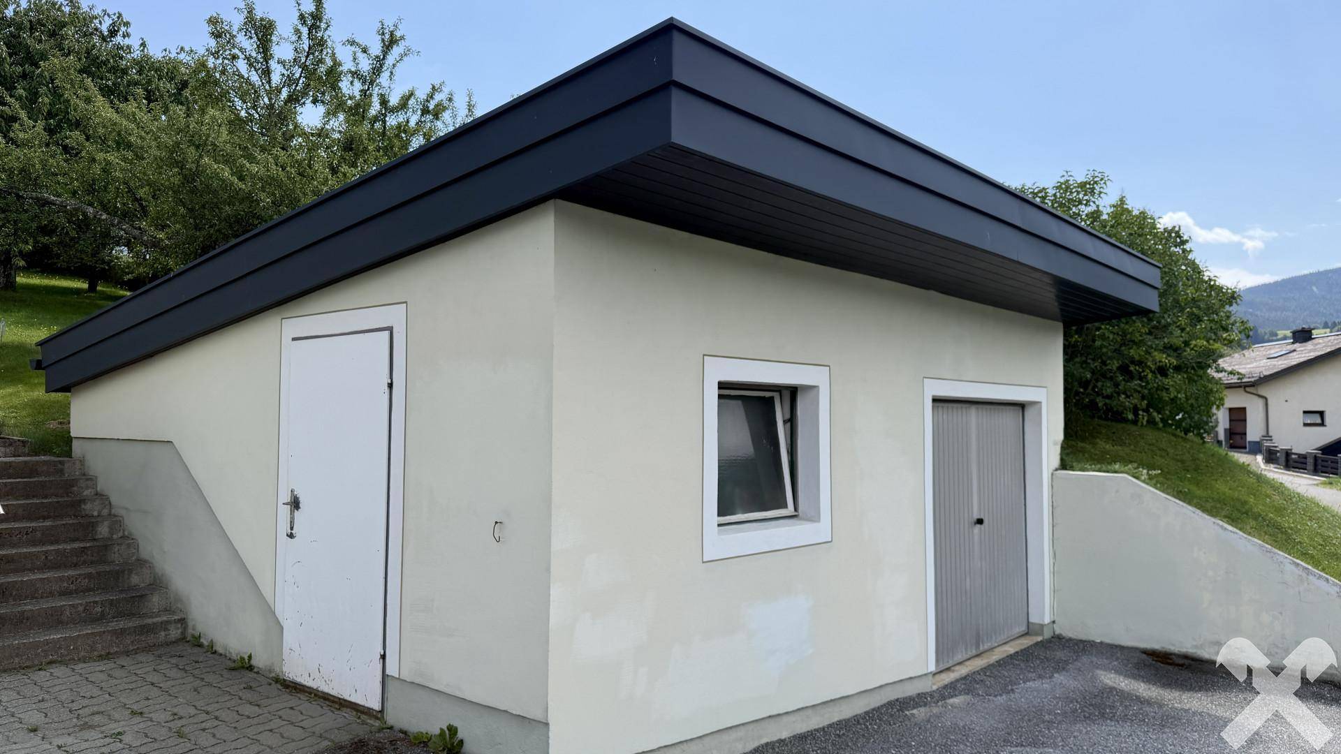 Separate Garage oder Abstellgebäude mit flachem Dach und Zugangstüren.