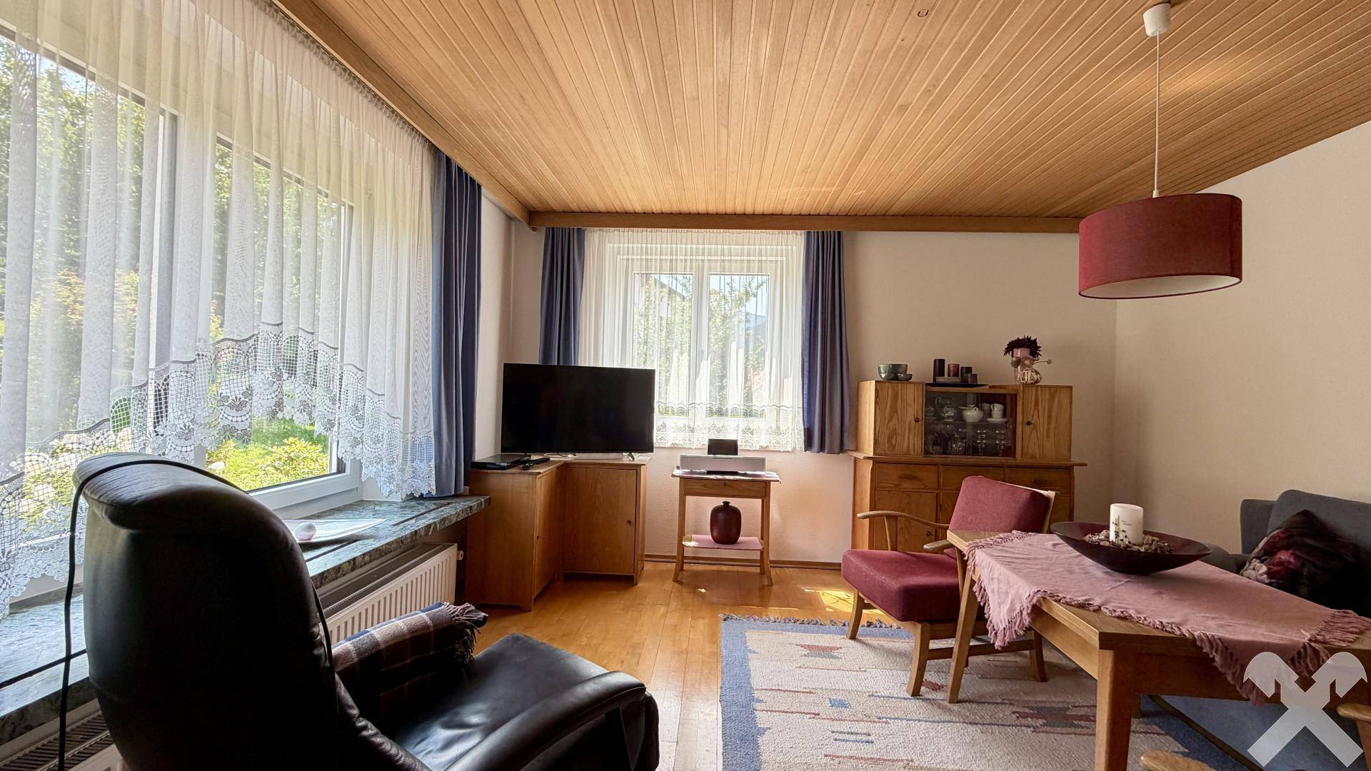 Gemütliches Wohnzimmer mit Holzbalkendecke, Parkettboden und traditioneller Einrichtung.
